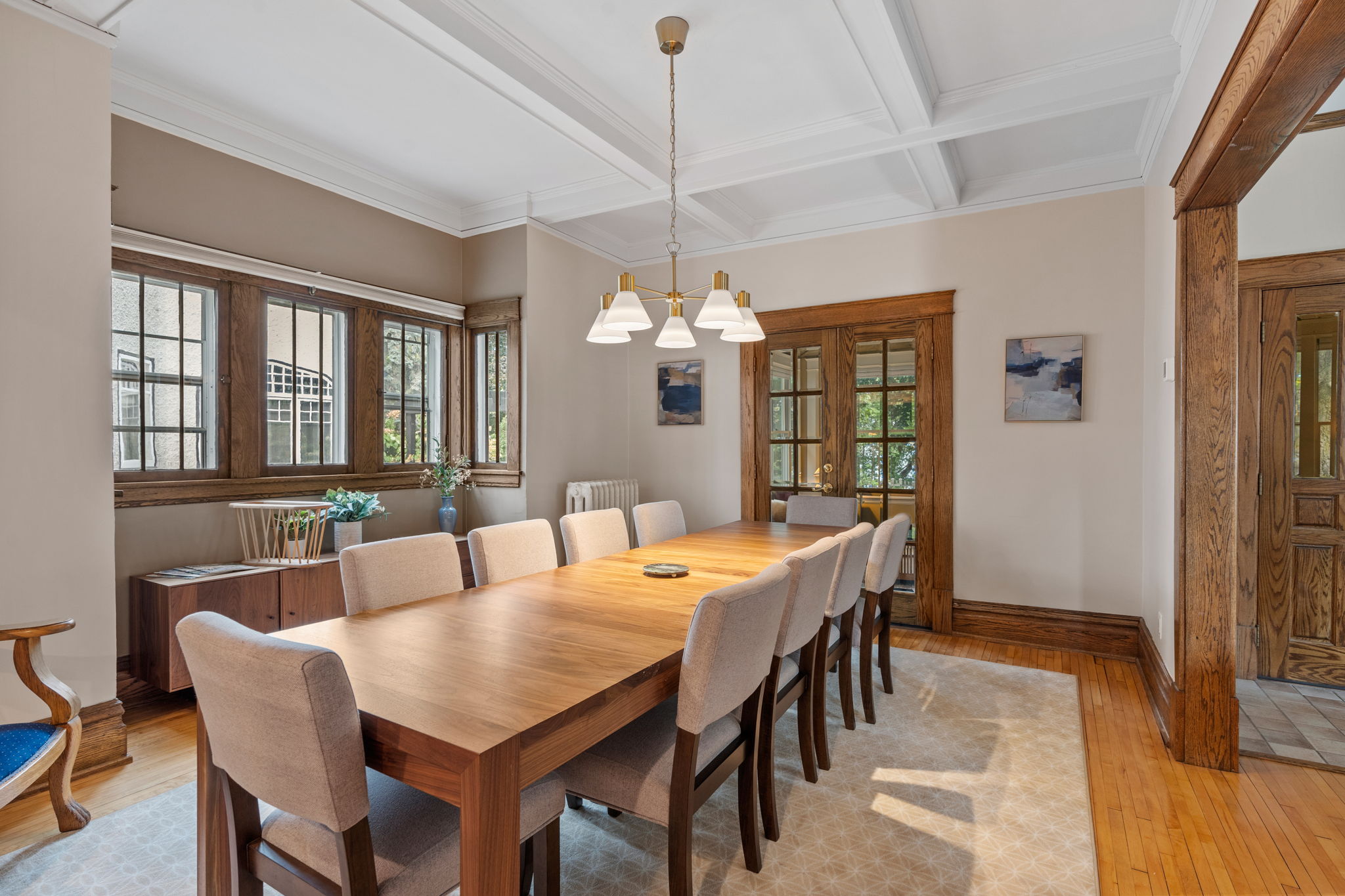 A spacious and elegant dining room with a long wooden table and natural light.