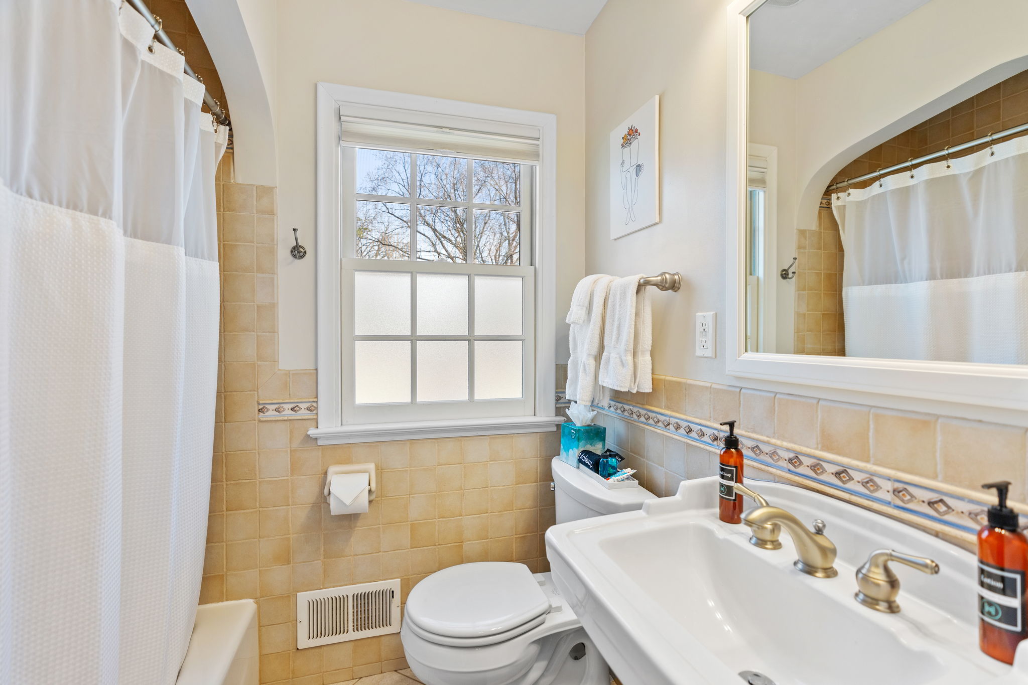 A bright and organized bathroom featuring classic fixtures and natural light.