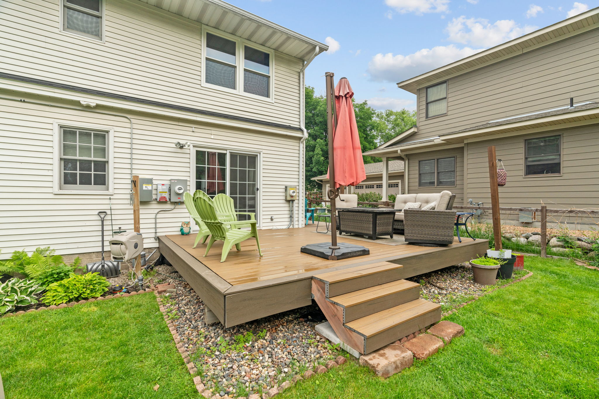 A cozy backyard deck featuring green chairs and a comfy seating area.