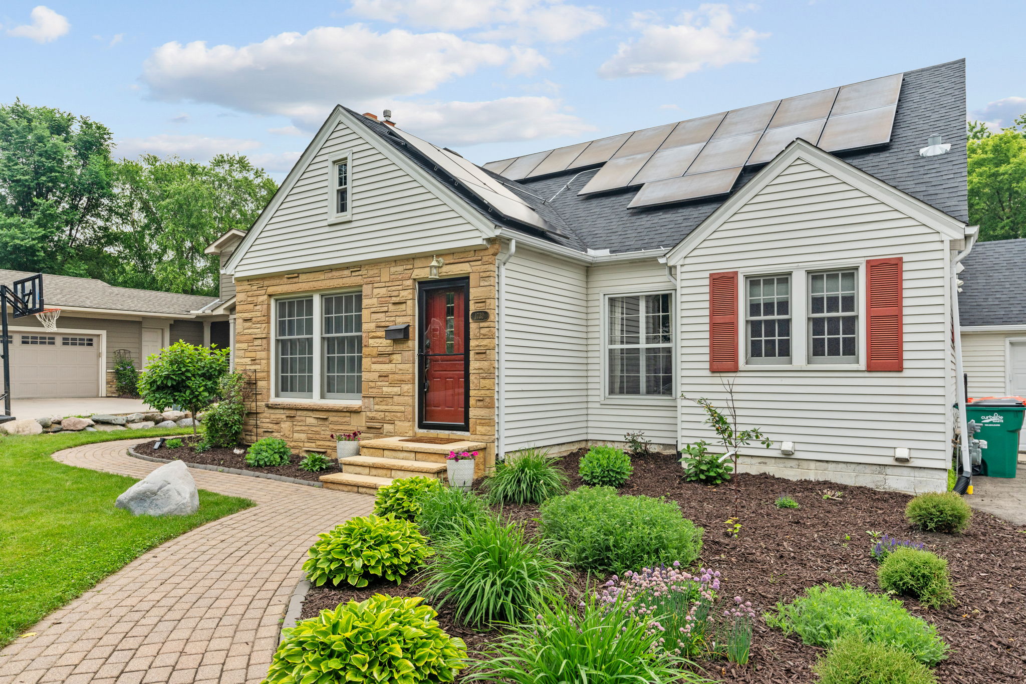 A beautifully landscaped home with solar panels and inviting red accents.