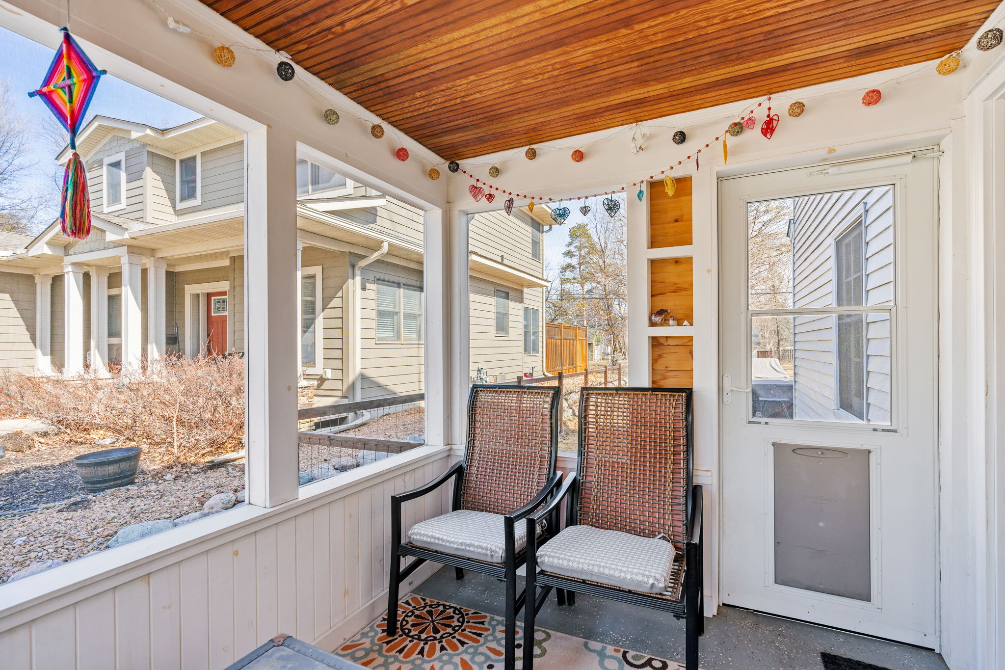 A cozy screened porch with wicker chairs and colorful decorations.