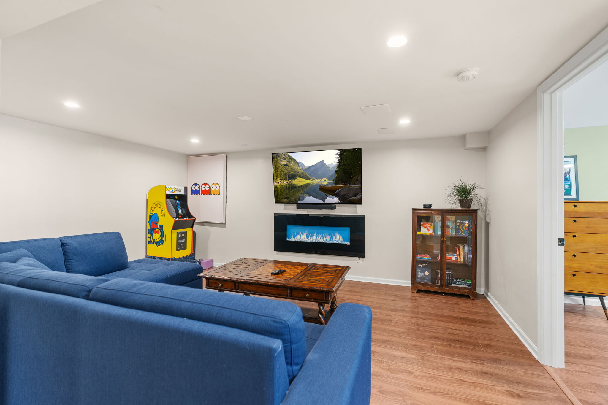 Cozy basement living area with a sectional sofa and arcade game.