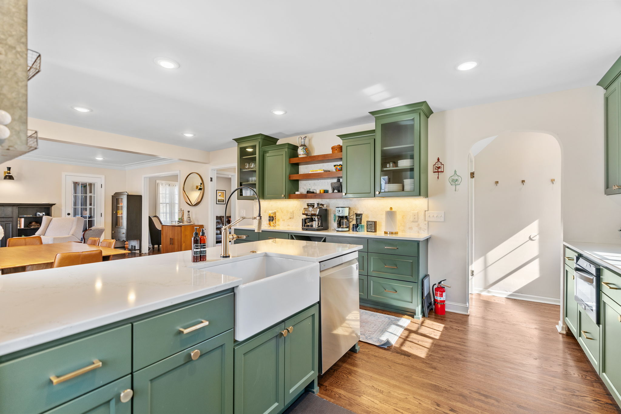 A modern kitchen featuring olive green cabinetry and an elegant island with a farmhouse sink.