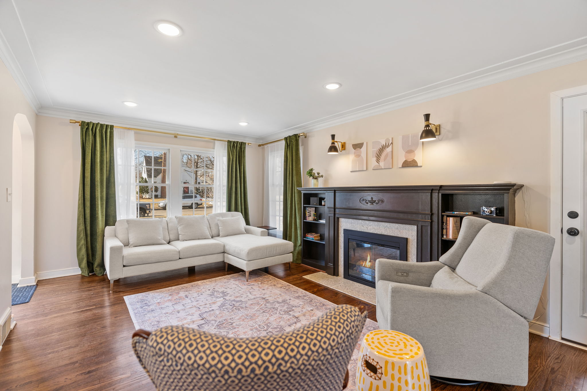 A modern and inviting living room featuring a sectional sofa, green curtains, and a fireplace.