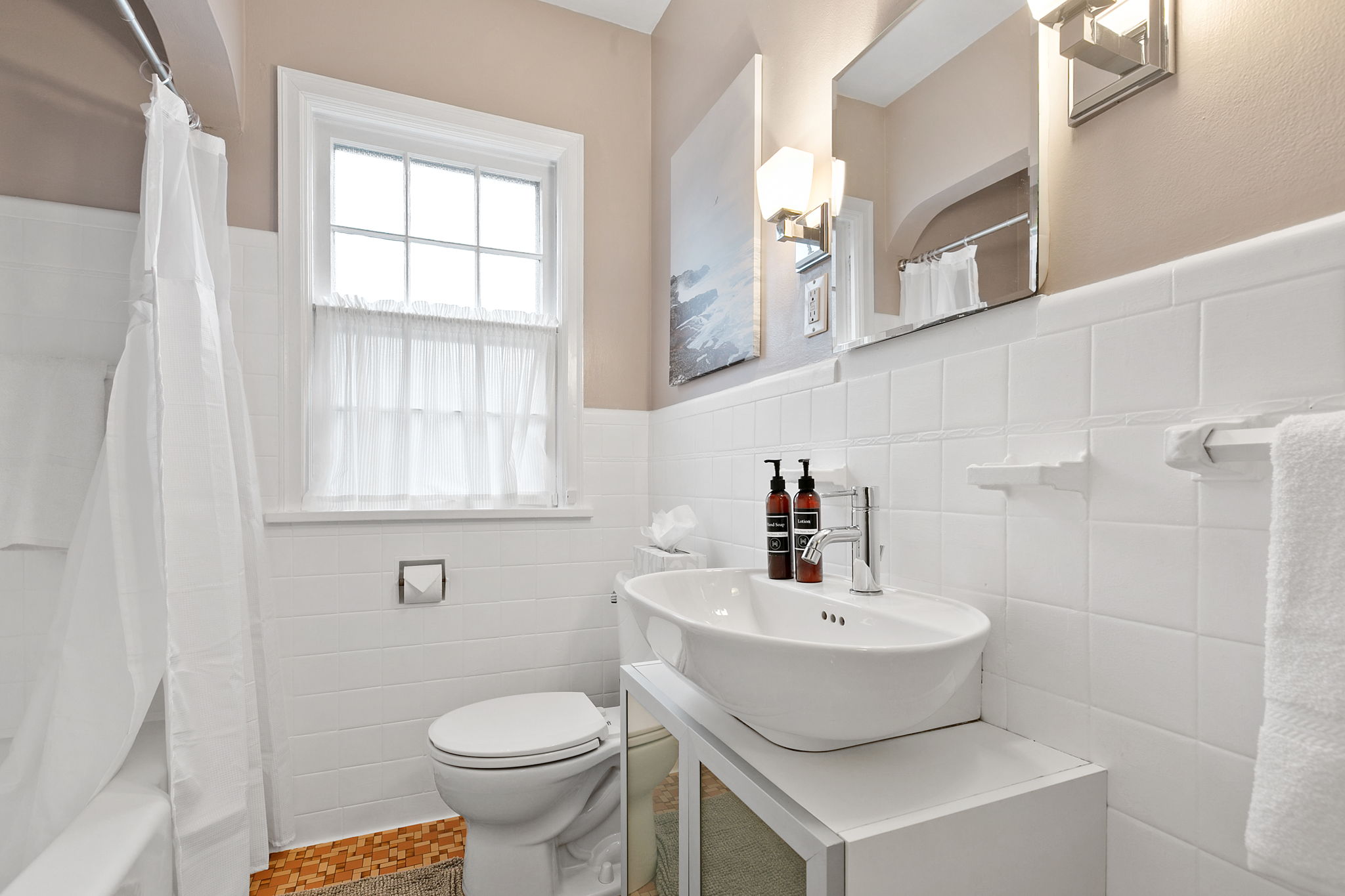 A modern bathroom featuring a bright design with an oval sink, natural light, and stylish accessories.