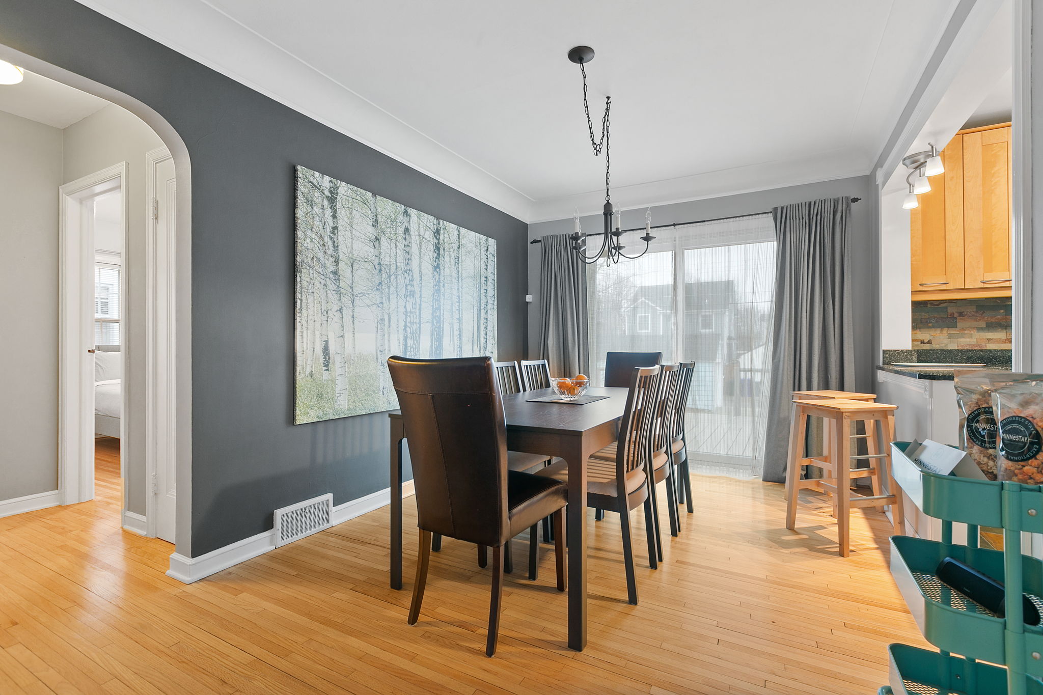 Modern dining room featuring a forest-themed artwork and ample seating.