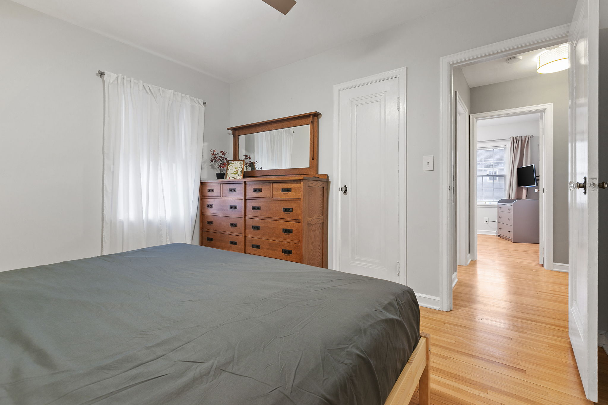 A warm and inviting bedroom with a stylish wooden dresser and bright ambiance.