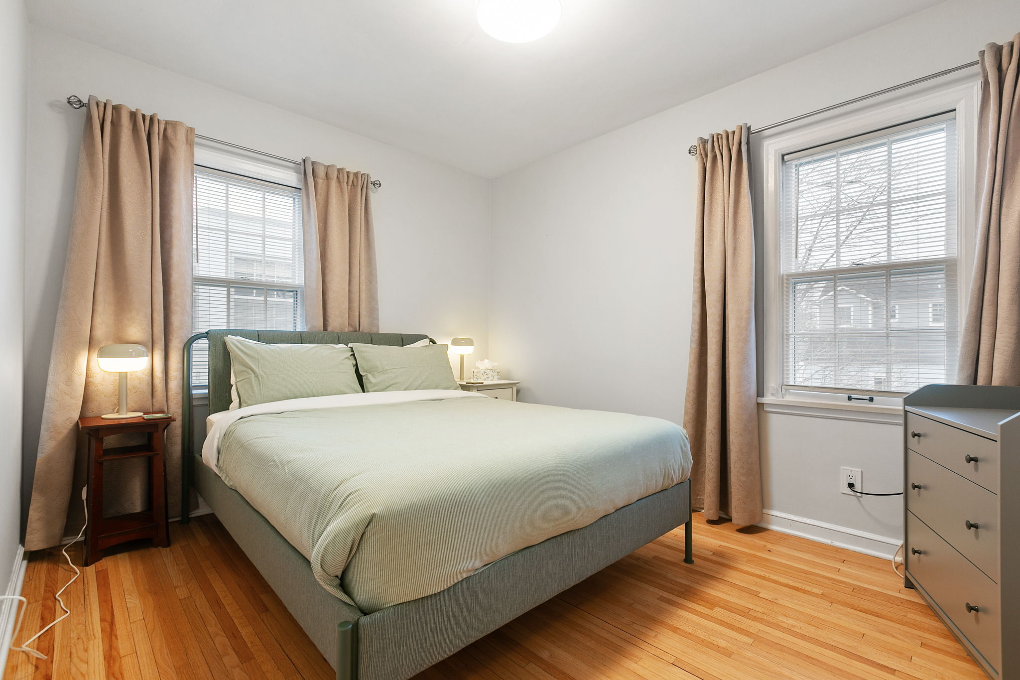 A serene and contemporary bedroom featuring a green bedspread and warm lighting.
