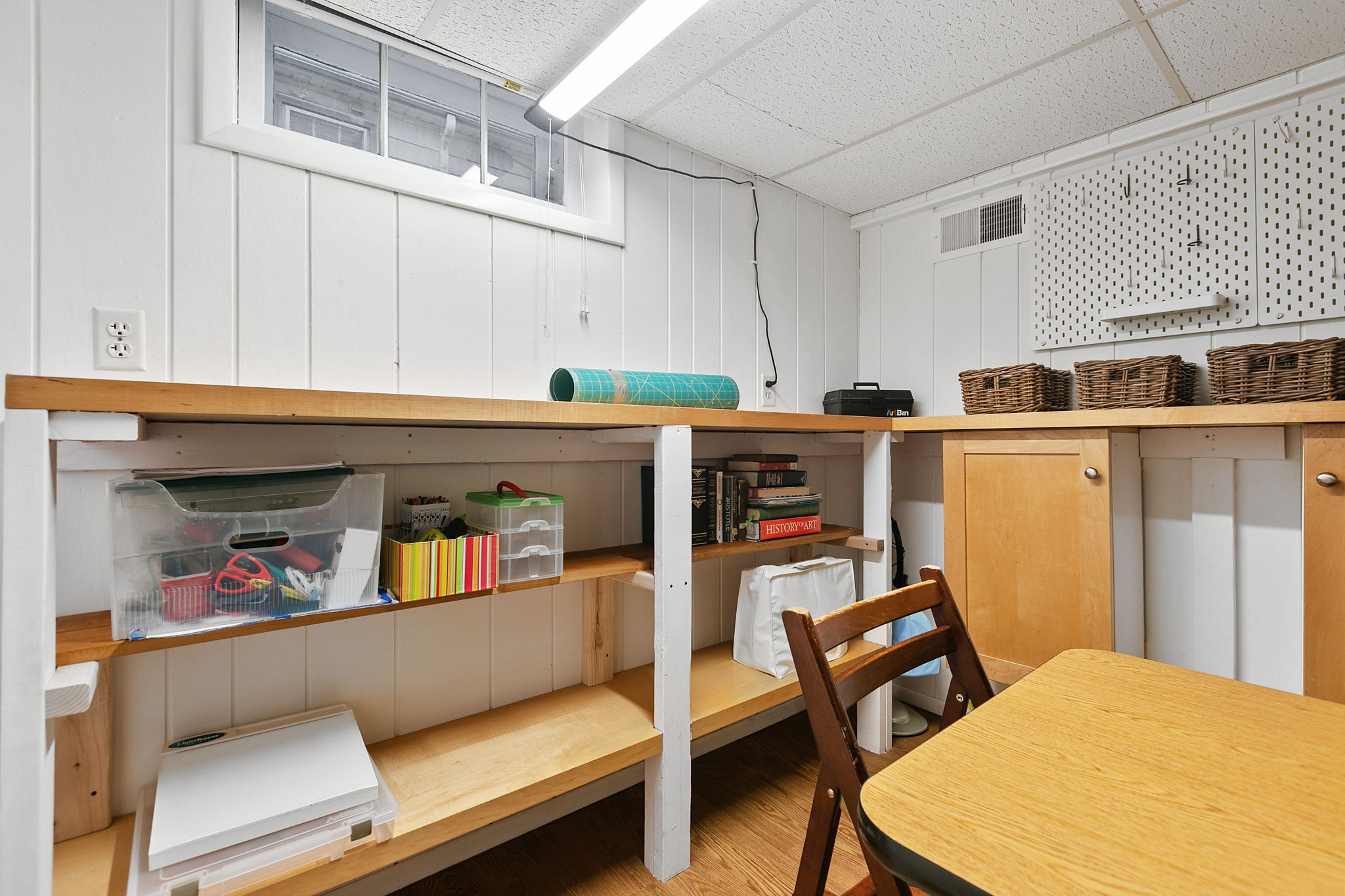 A neat and organized basement workspace with craft supplies and storage.