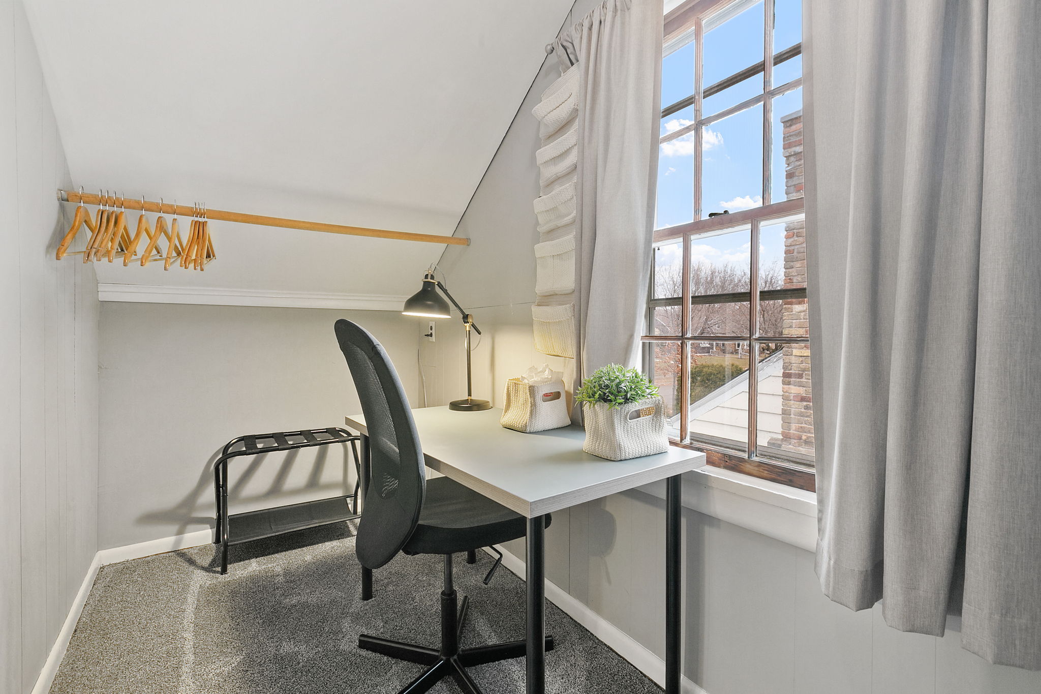 A minimalist workspace in an attic, featuring a desk, chair, and decorative elements.