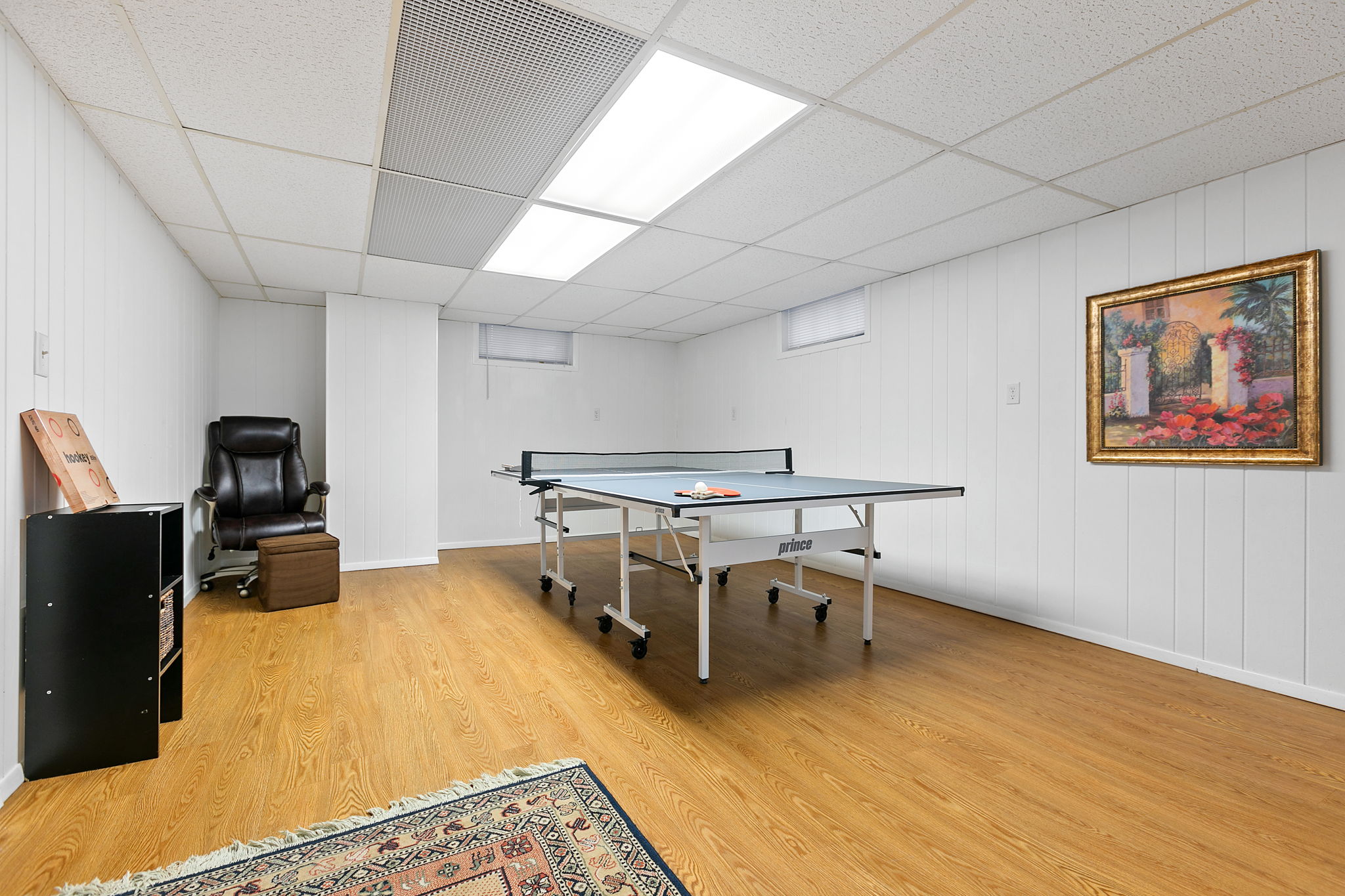 A modern basement game room featuring a ping pong table and cozy seating.