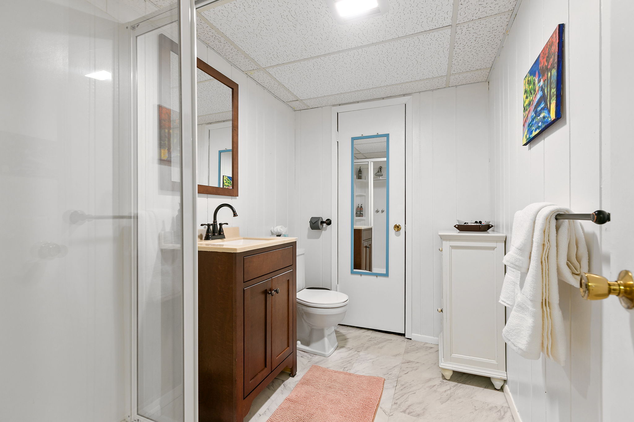 A modern, tidy bathroom featuring a sleek shower and dark wood vanity.