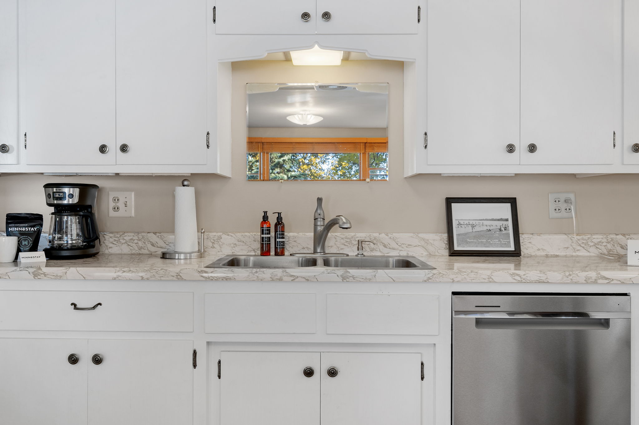 A bright and modern kitchen featuring white cabinets and marble countertops.
