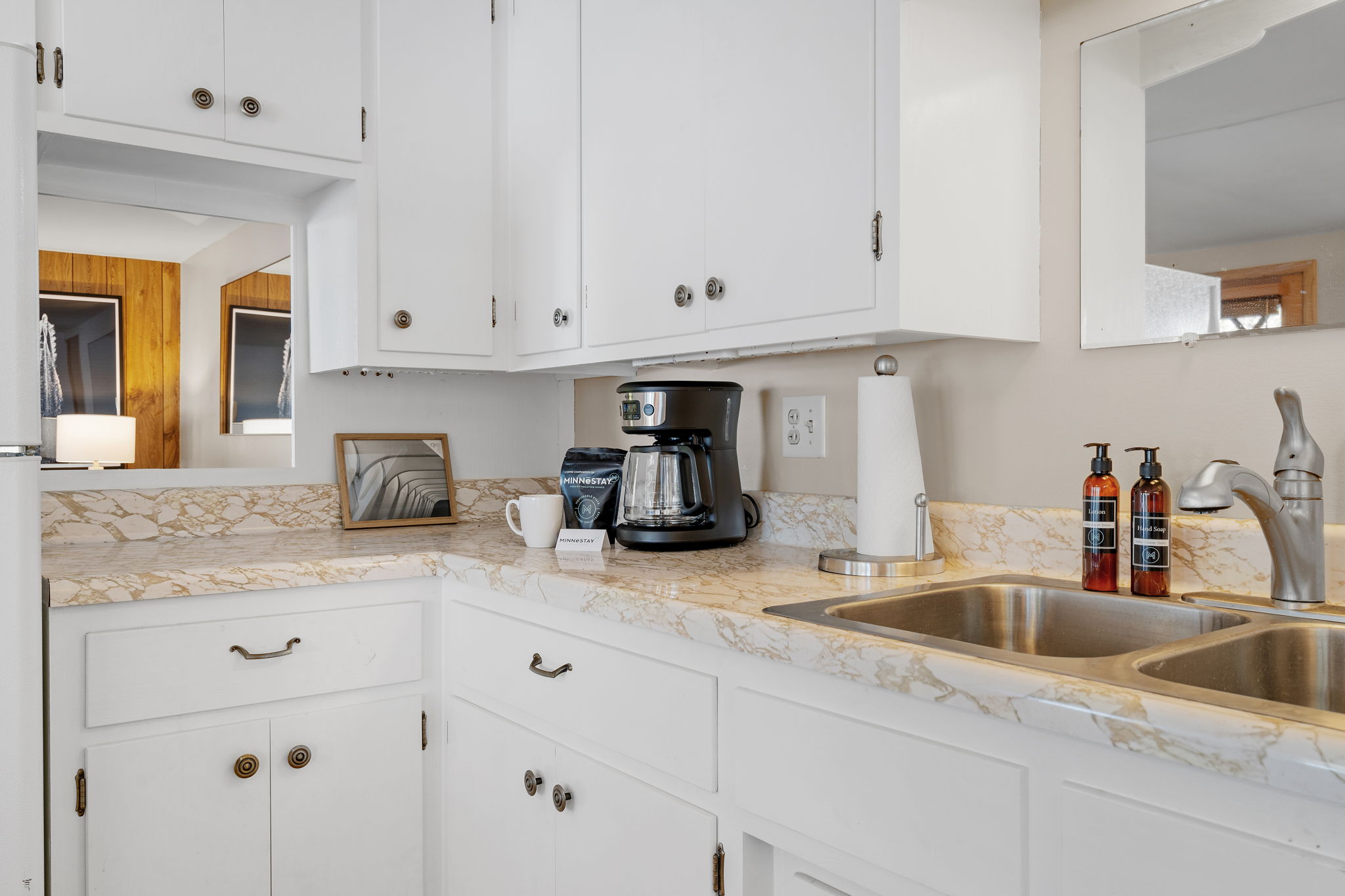 A cozy kitchen with white cabinets and a coffee setup.
