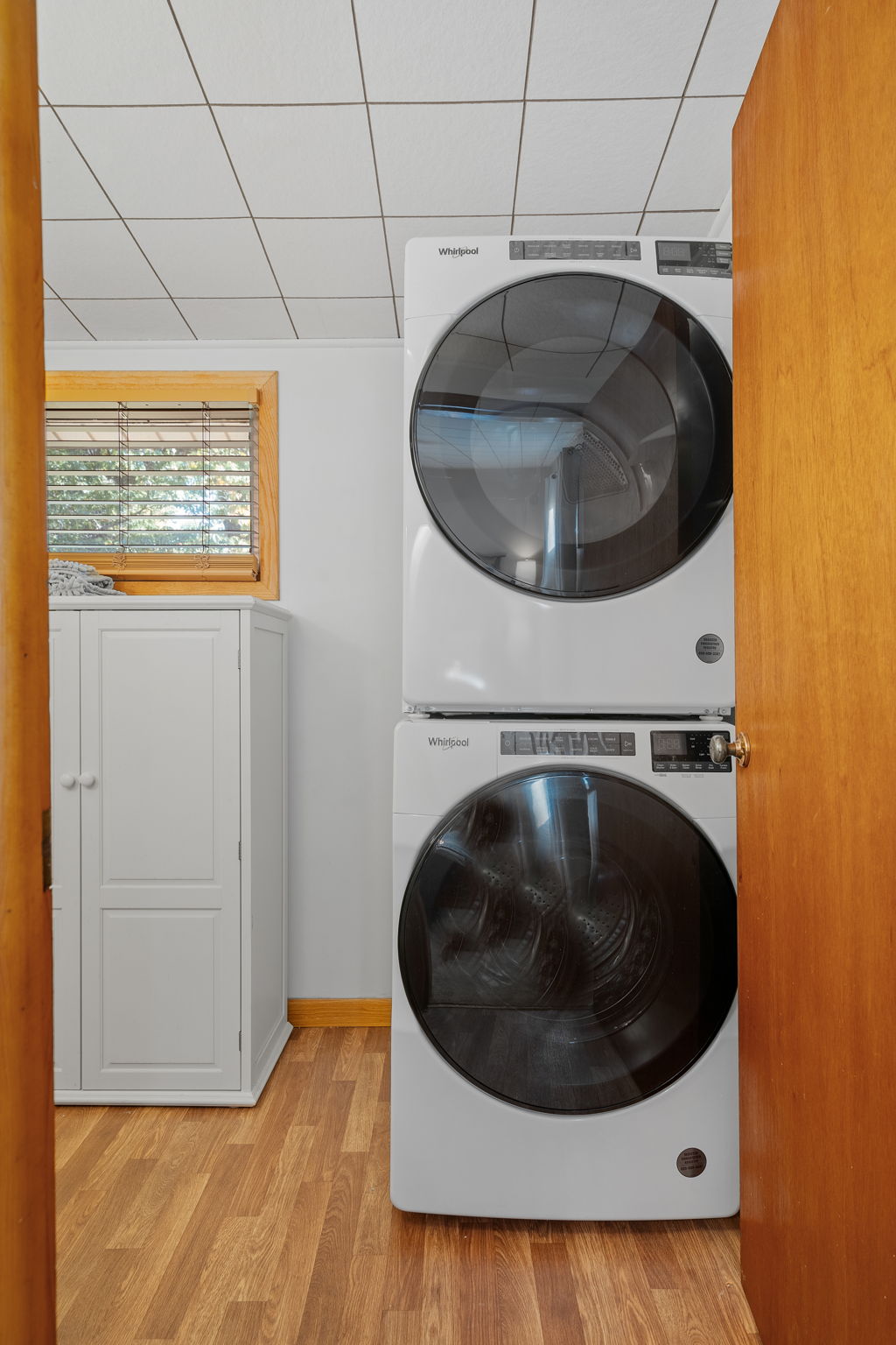 Modern stacked Whirlpool washer and dryer in a cozy laundry room.