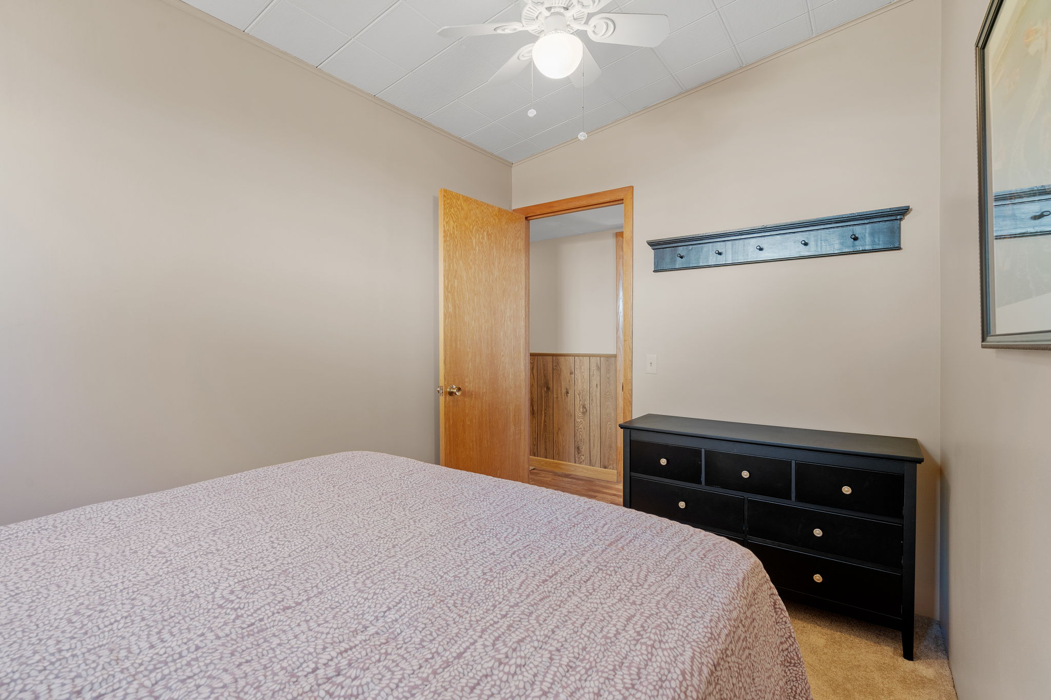 A cozy bedroom with beige walls, a textured quilt, and a stylish dresser.