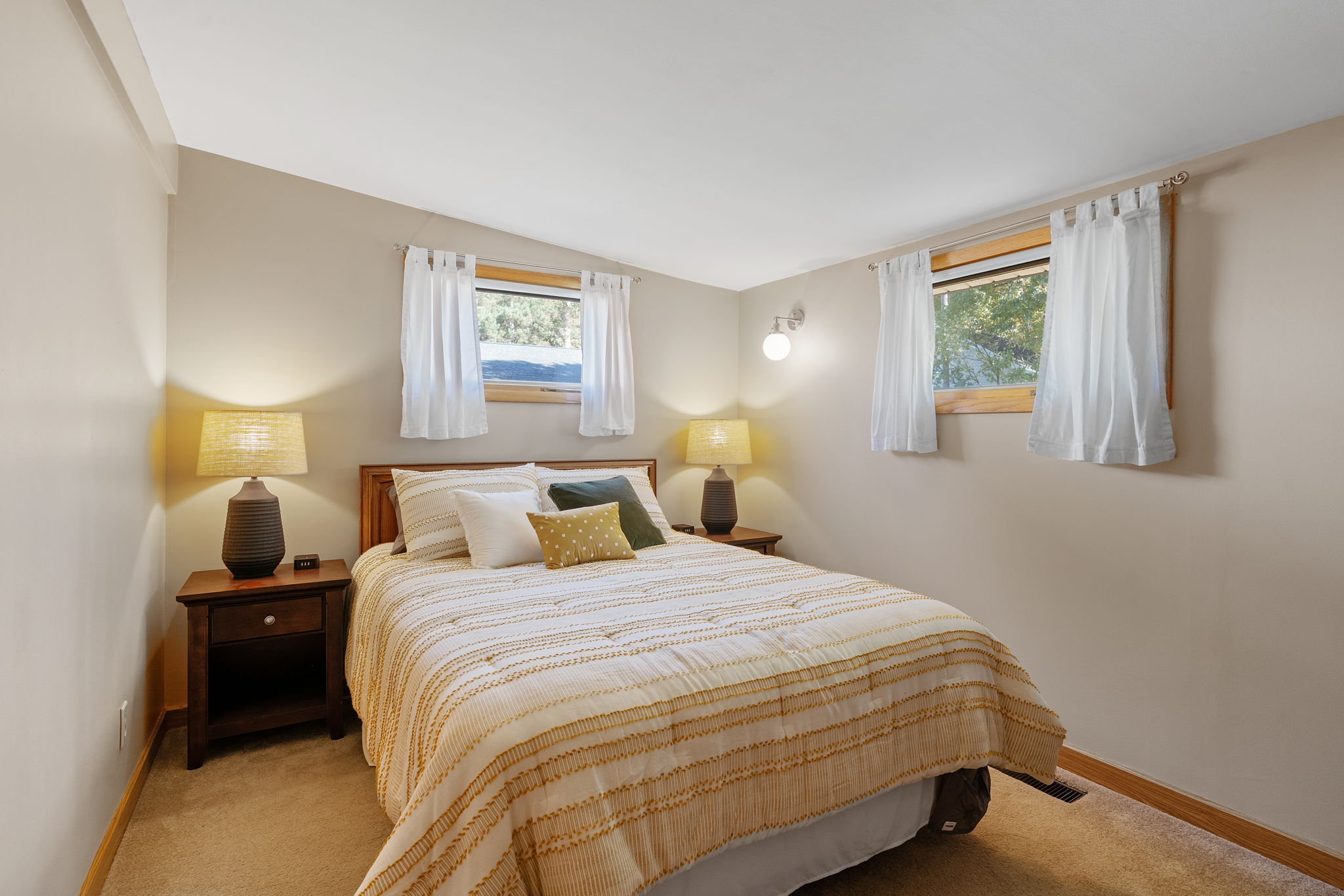A cozy bedroom with a light comforter and warm lighting.