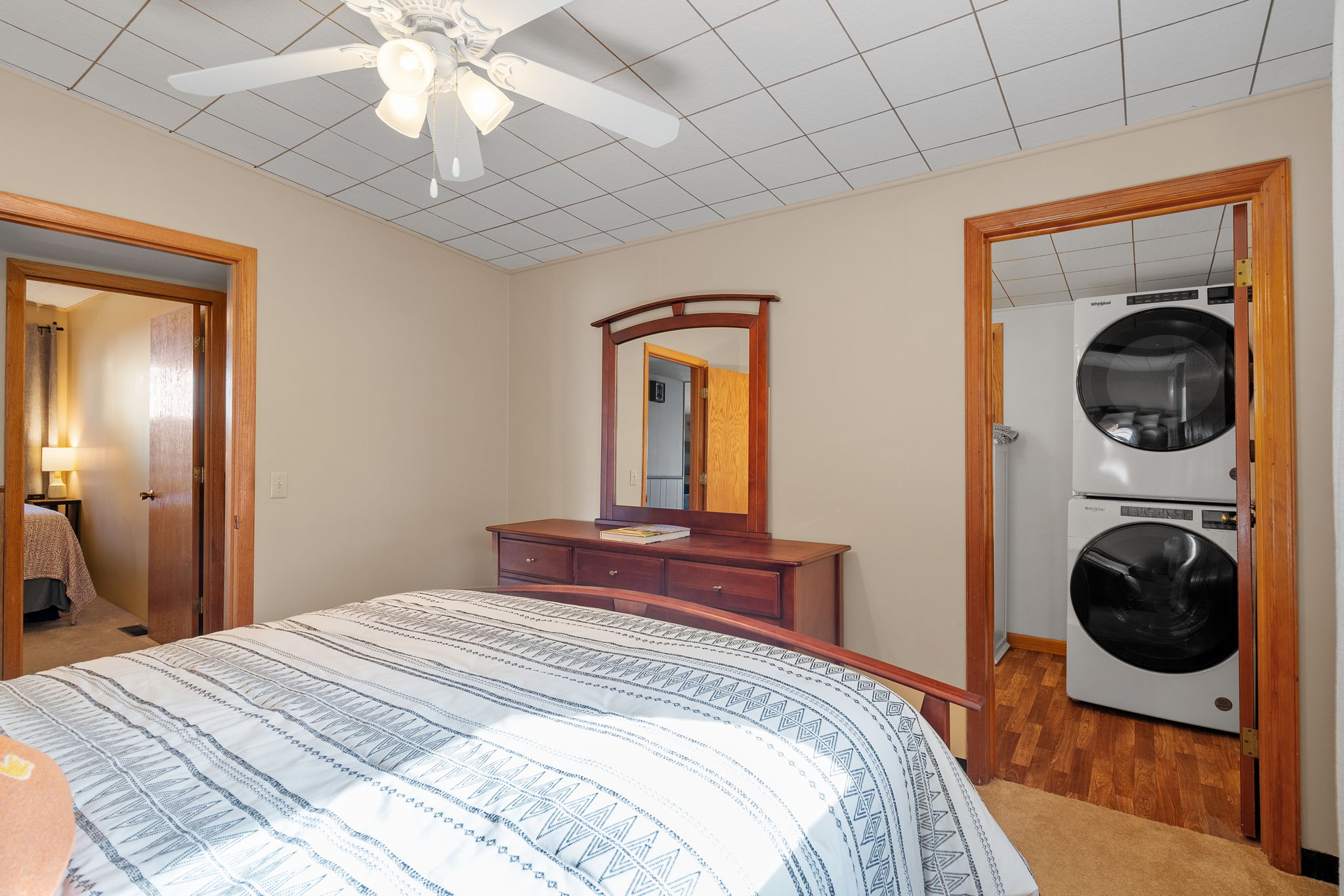A cozy bedroom featuring a bed, dresser, and adjoining laundry area.