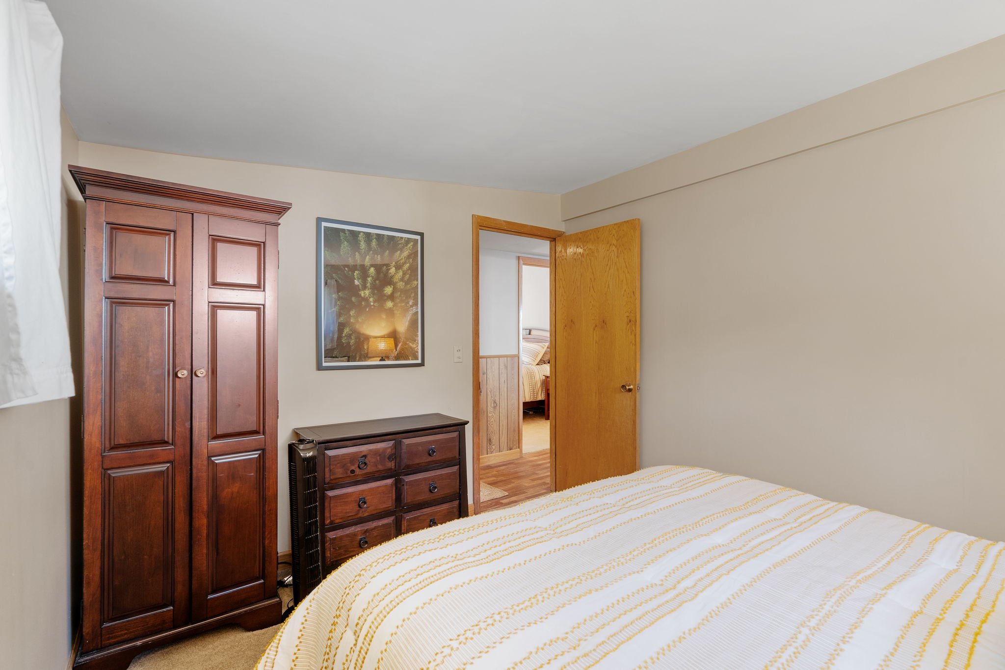 A cozy bedroom with wooden furniture and white bed linens.