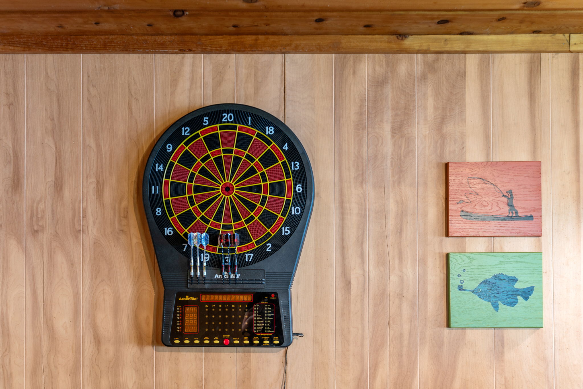 A dartboard and decorative wooden plaques in a cozy recreation room.