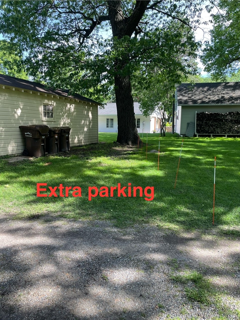 A grassy area designated as extra parking, featuring trees and nearby buildings.