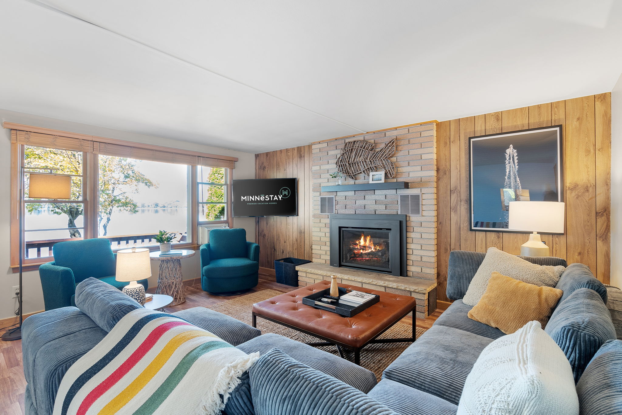 Cozy living room with a fireplace and large windows showcasing a lake view.
