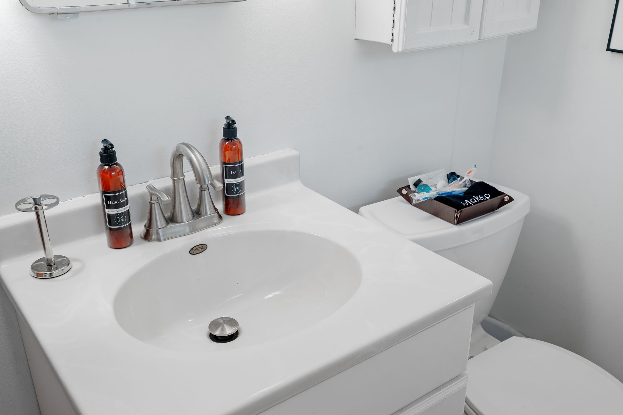 A modern bathroom countertop with soap, lotion, and essentials organized on the toilet.