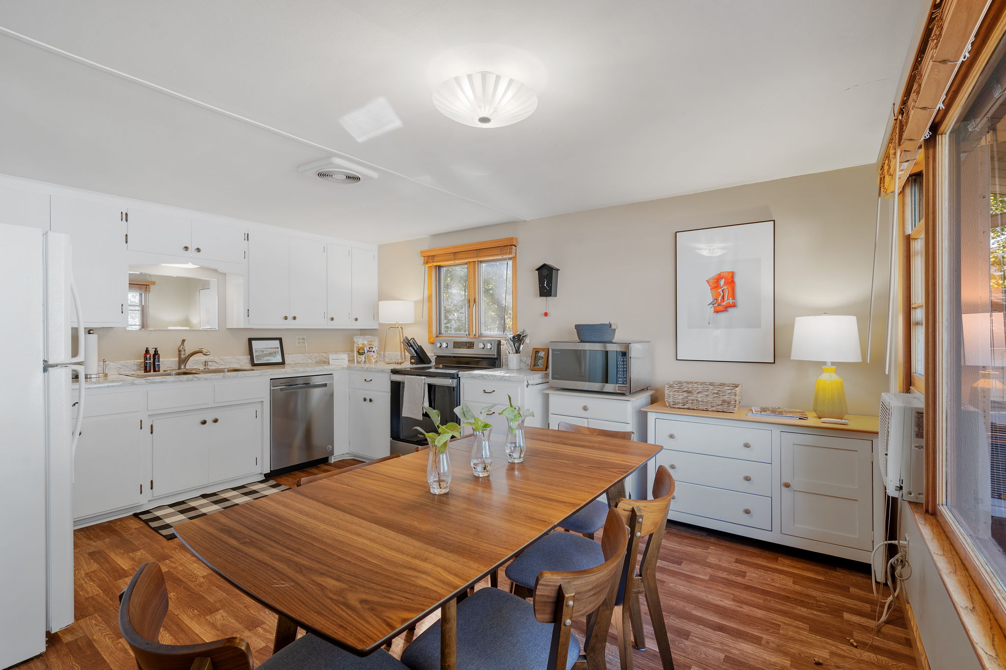 A modern kitchen and cozy dining area featuring elegant white cabinetry and a wooden dining table.