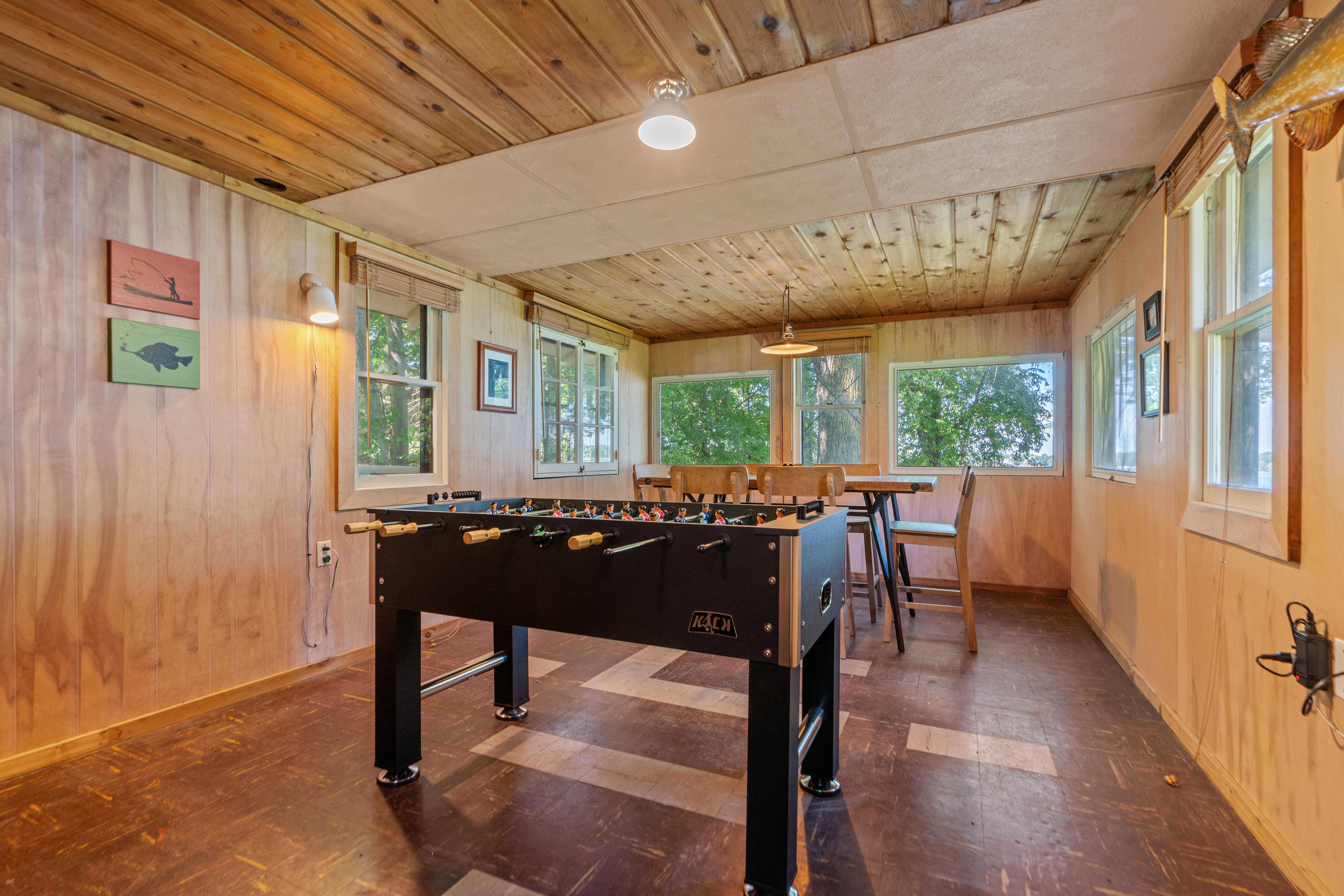A cozy game room with a foosball table and large windows overlooking nature.