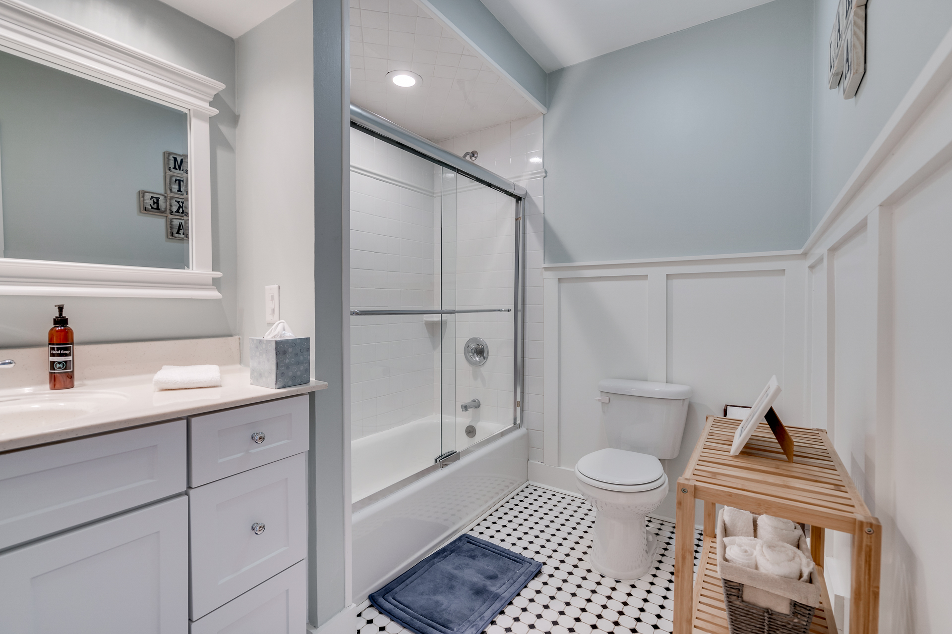 A modern bathroom with a stylish design featuring a glass shower, light colors, and vintage floor tiles.