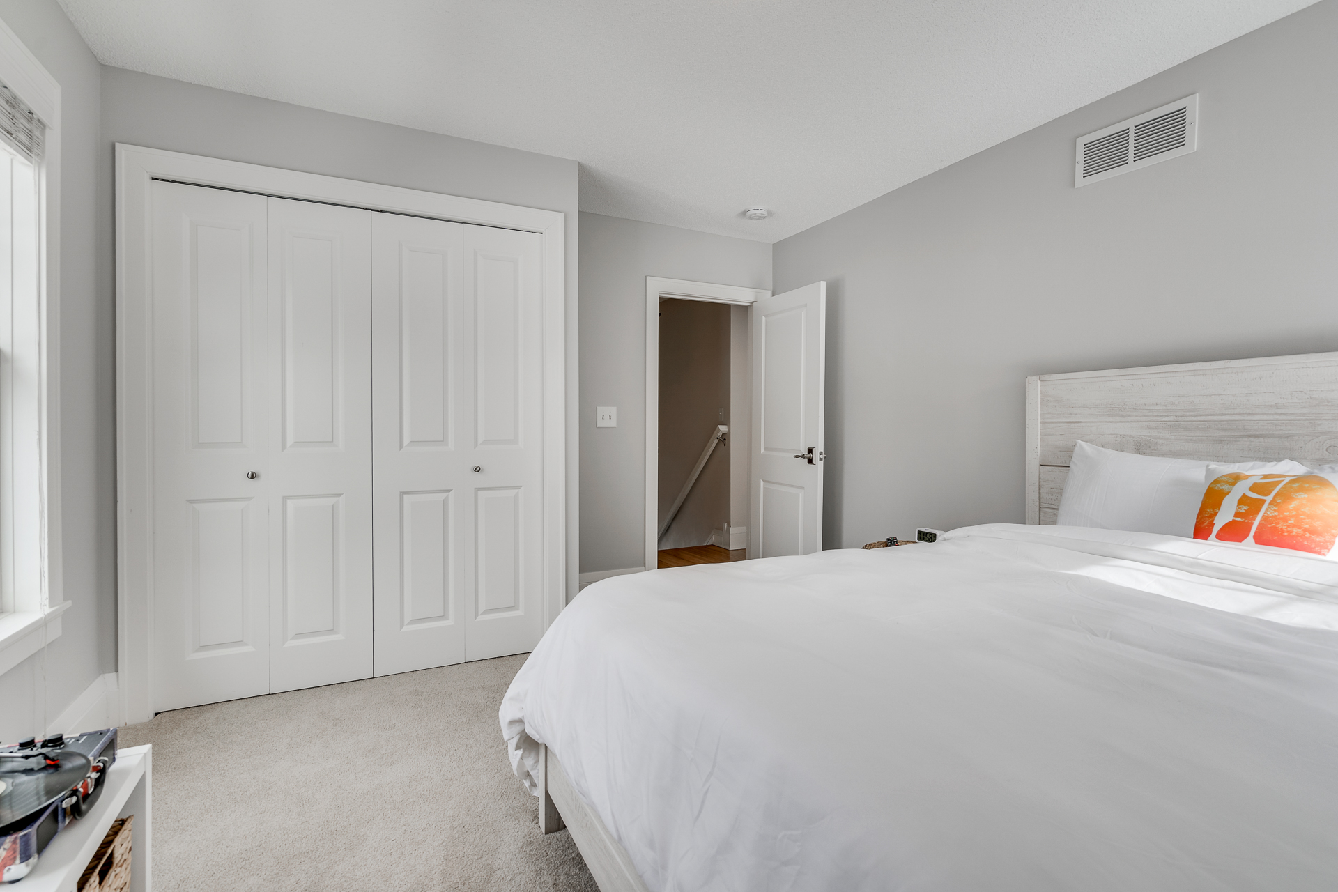 A bright and modern bedroom featuring a king-sized bed and soft gray walls.