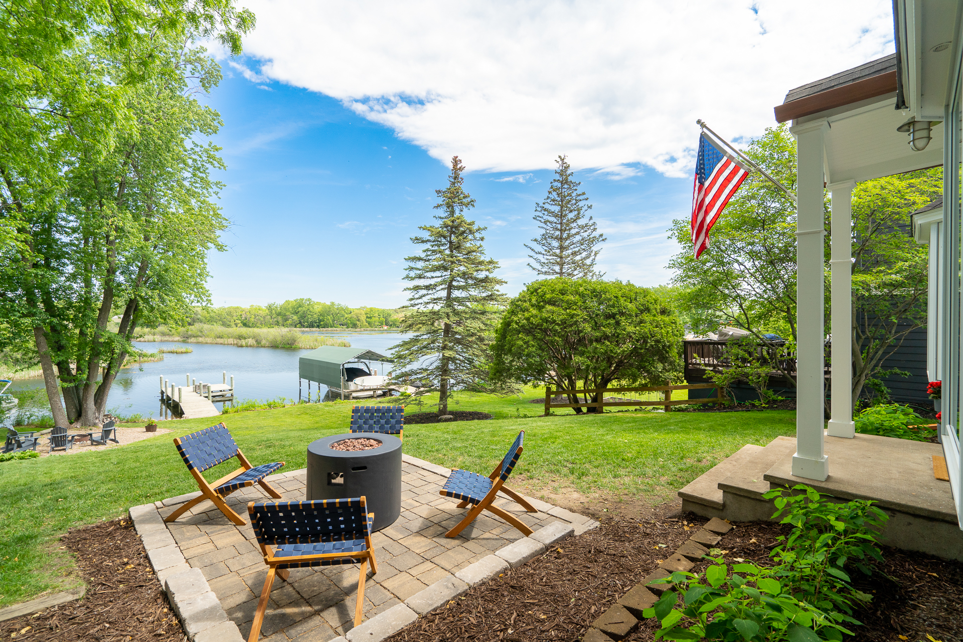 Outdoor seating area by the lake with fire pit and American flag.