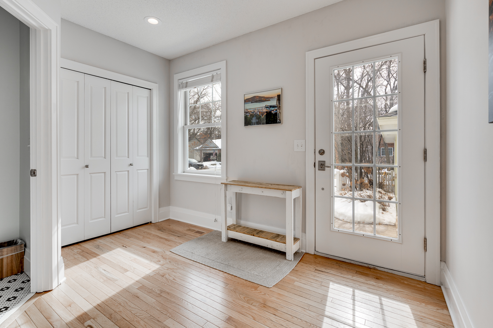 A bright and inviting entryway with natural light, wooden accents, and a touch of outdoor scenery.