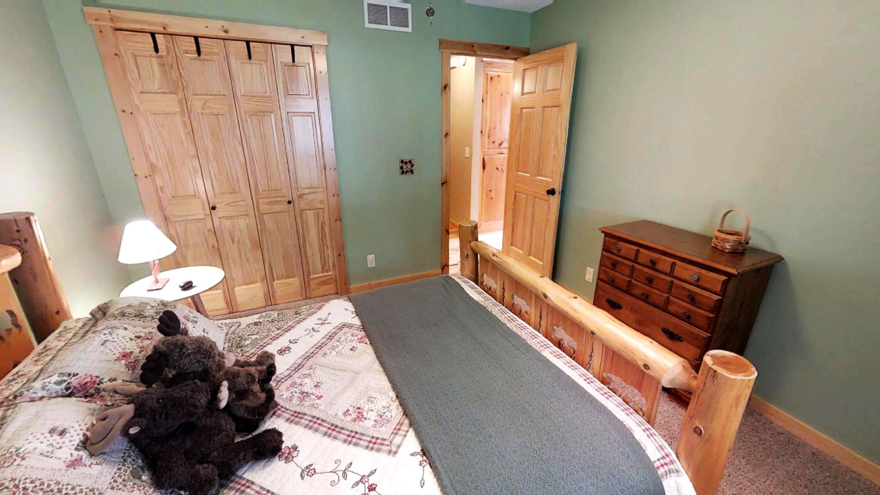 A cozy rustic bedroom featuring a log bed, wooden furniture, and soft color tones.
