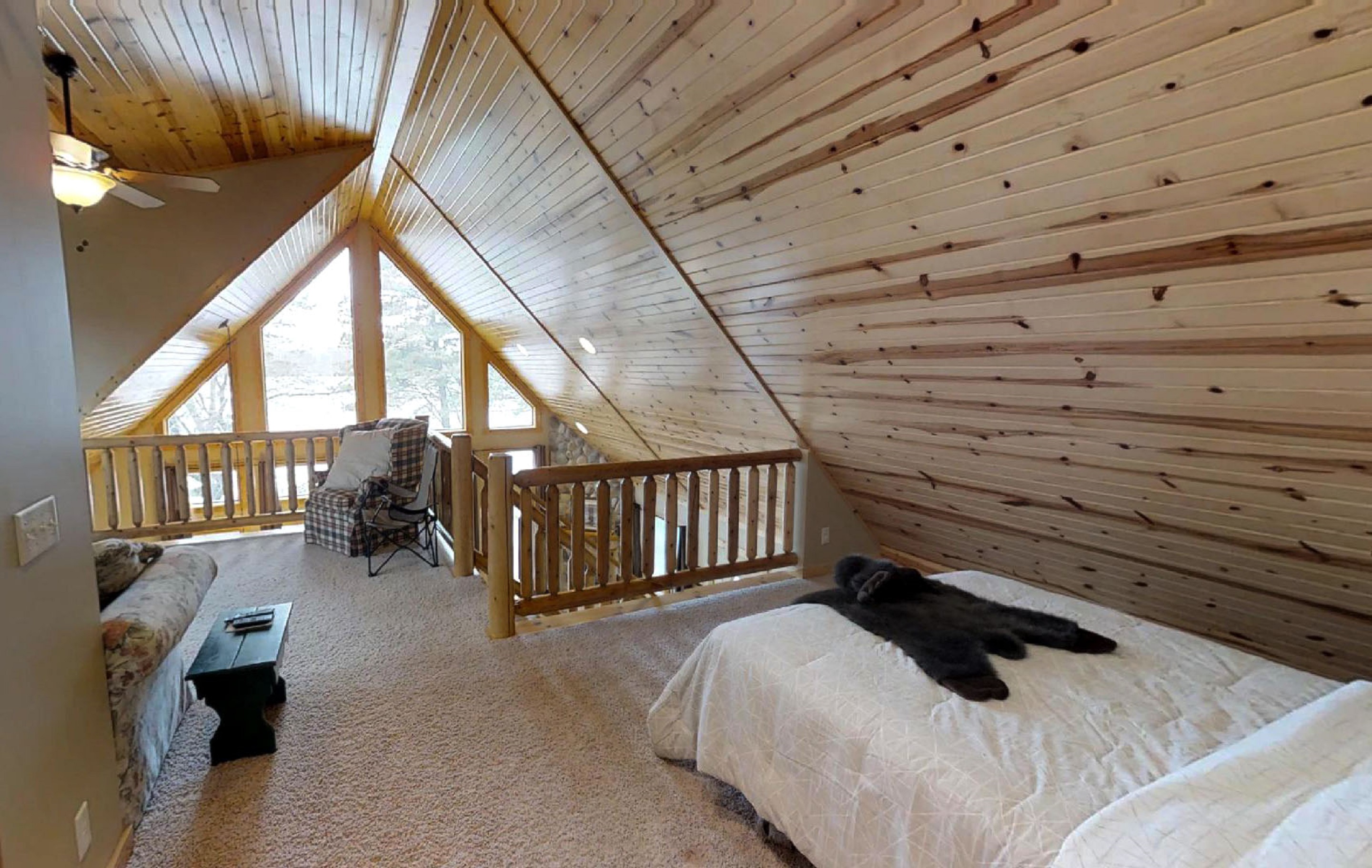 A rustic loft bedroom with wooden finishes and cozy seating.