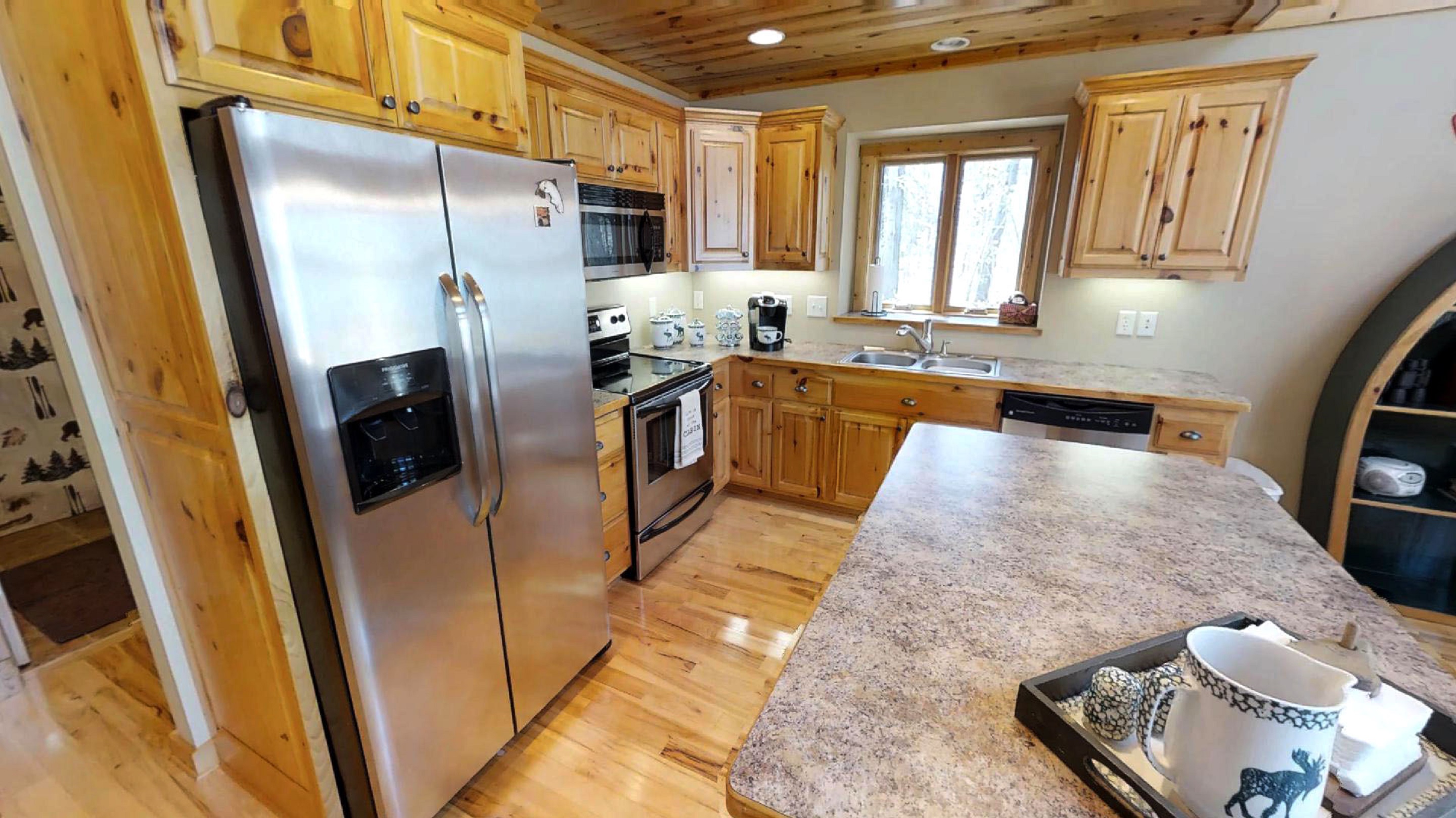 A cozy rustic kitchen with wooden cabinetry, stainless steel appliances, and a large window for natural light.
