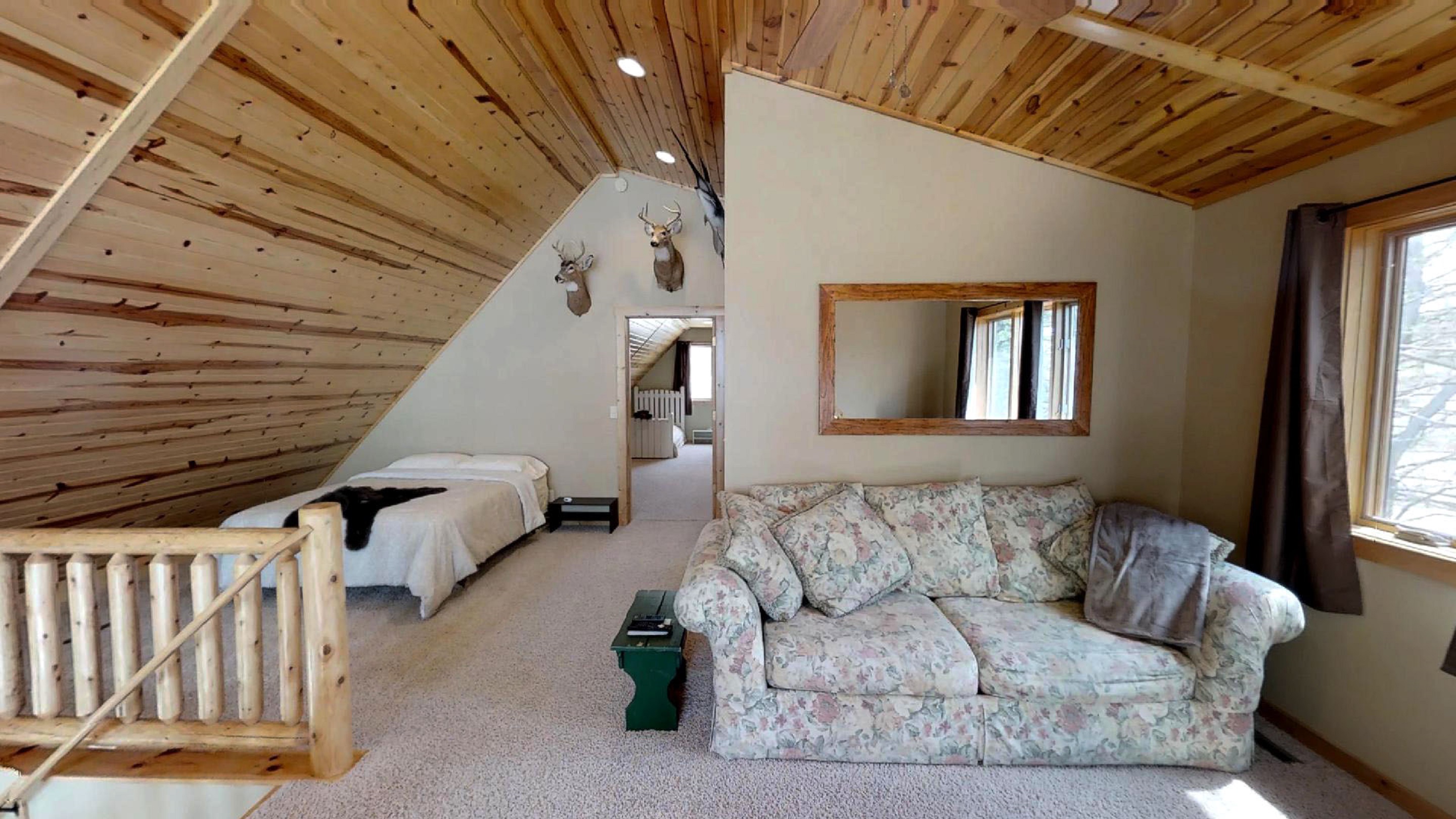 A cozy loft bedroom with a floral couch and rustic charm.