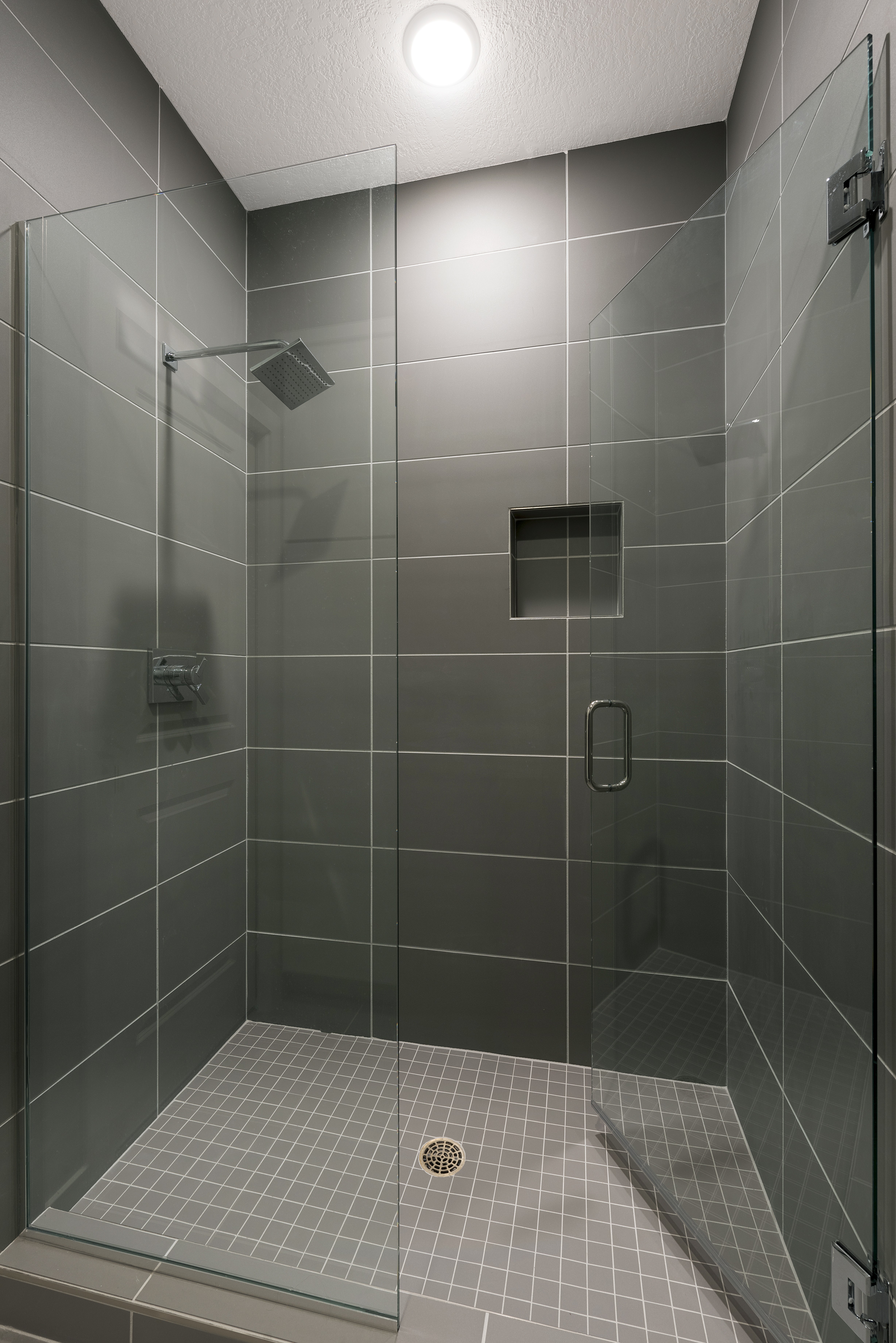 A sleek and modern glass shower enclosure with gray tile accents.