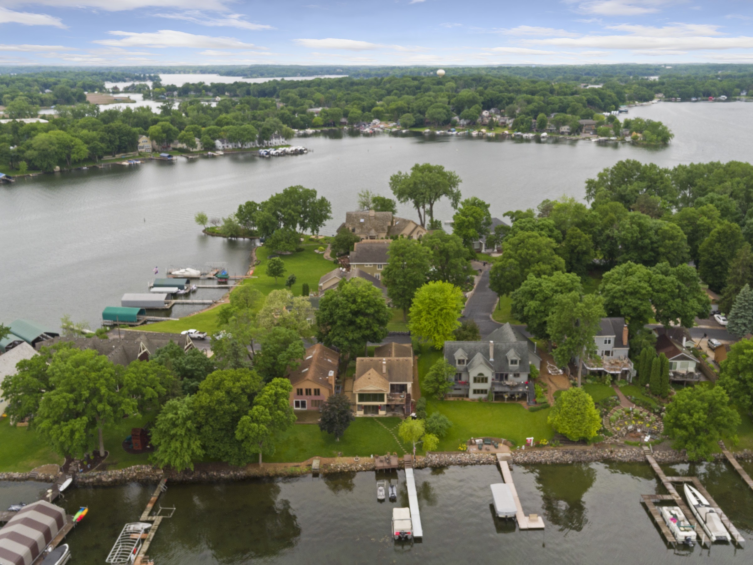 Aerial view of a lakeside neighborhood with lush greenery and houses lining the shore.