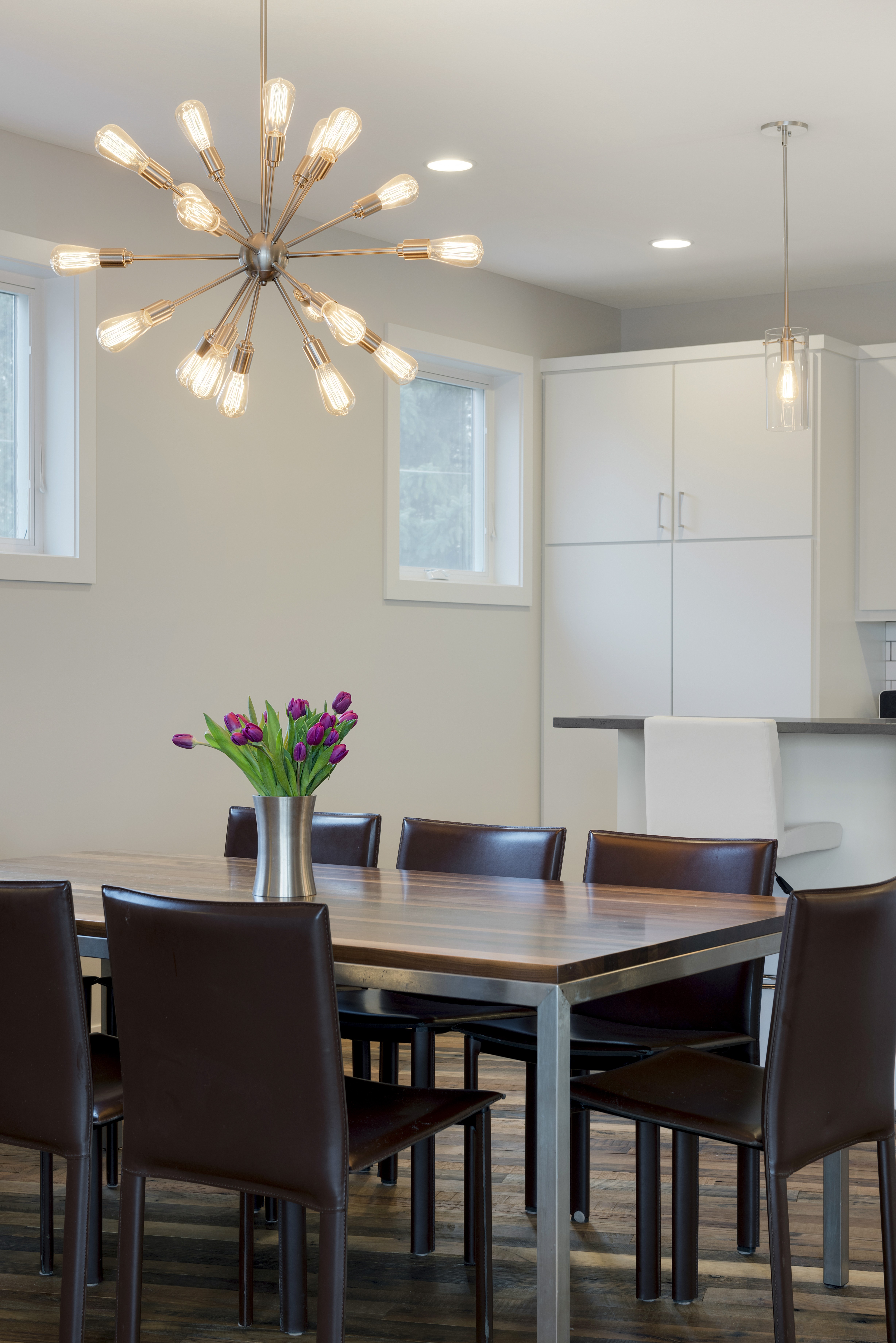 A modern dining space featuring a stylish chandelier and fresh flowers.