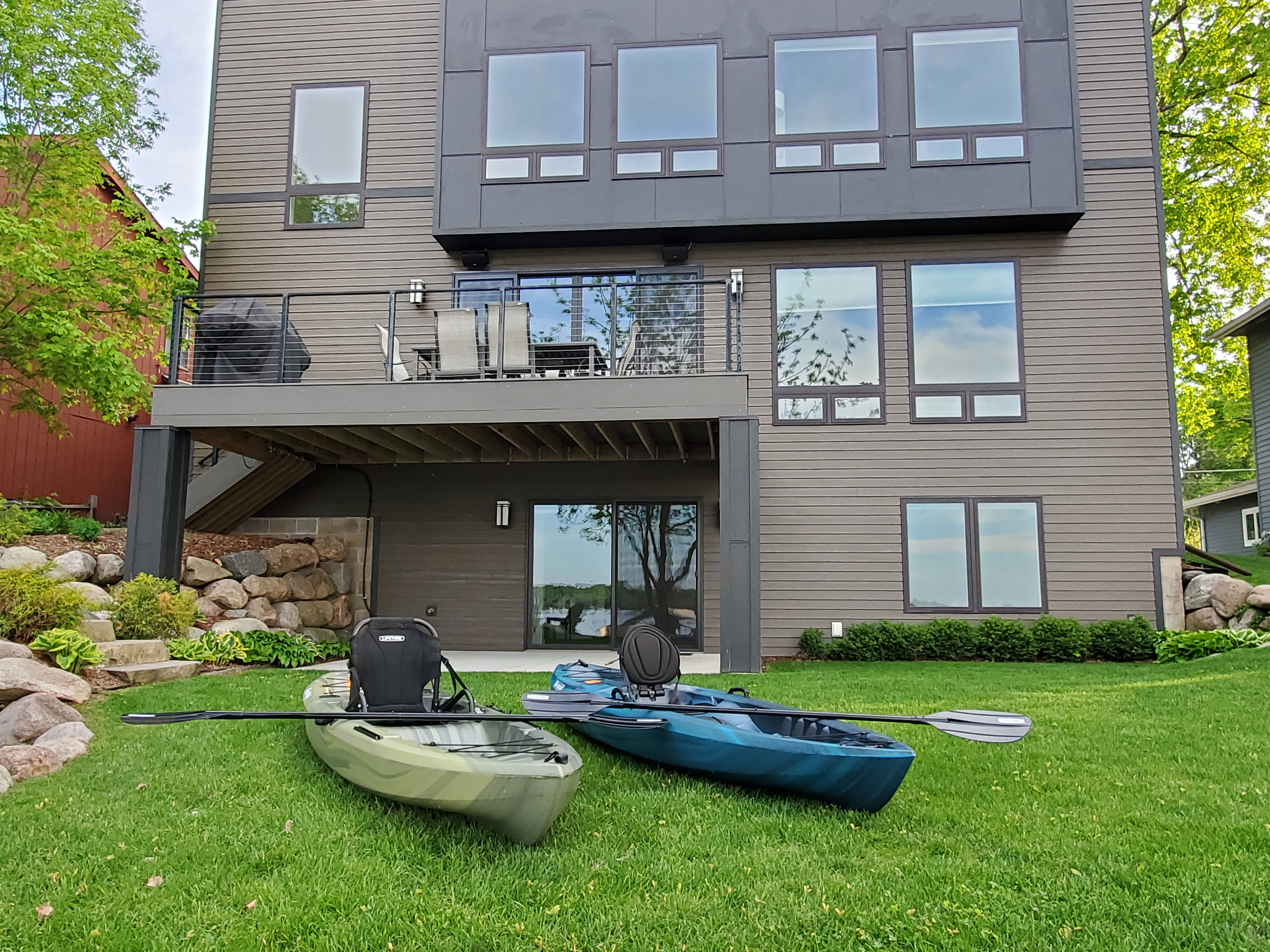 A modern lakeside house with kayaks on the lawn.