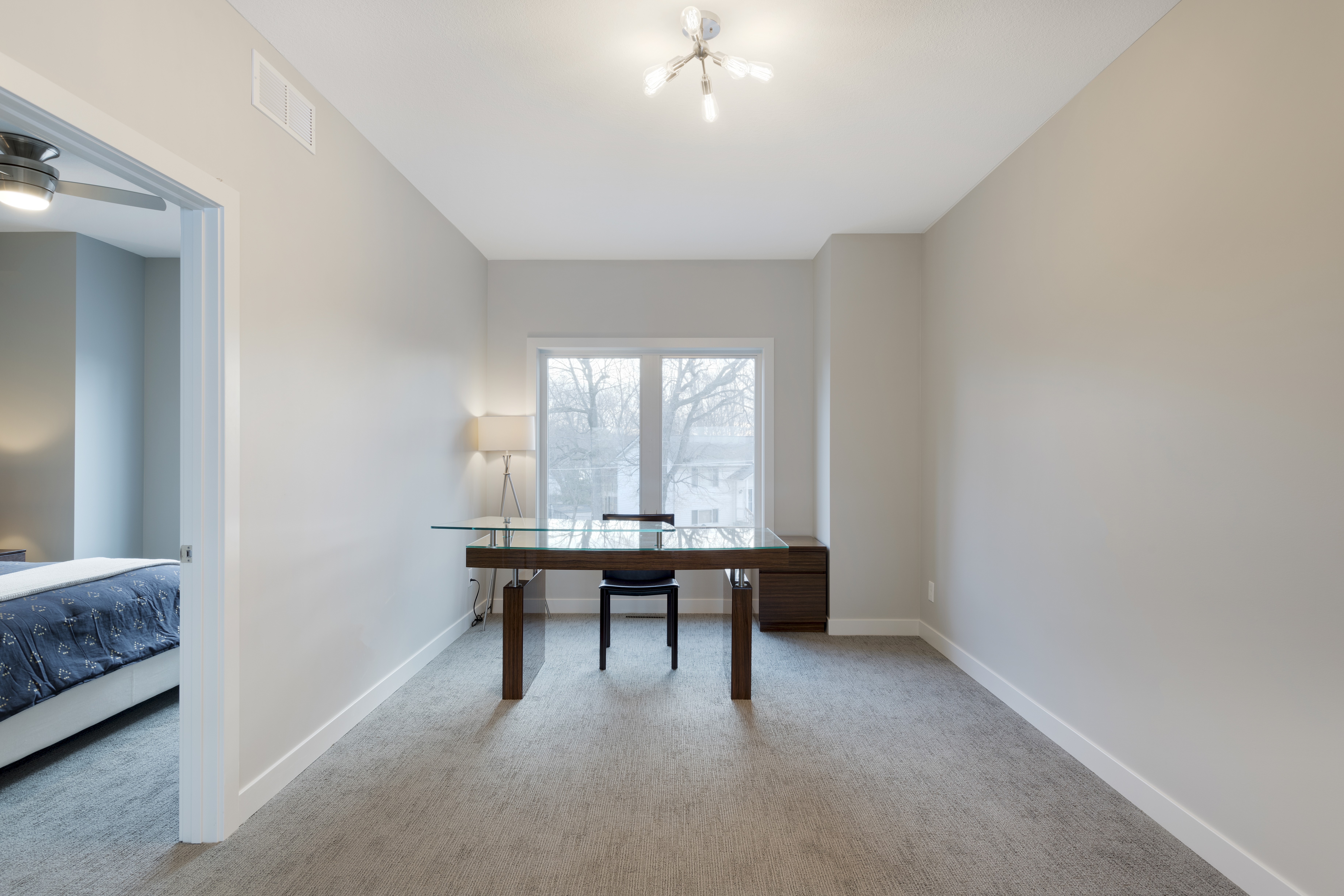 A modern minimalist office space with a glass desk and a cozy ambiance.