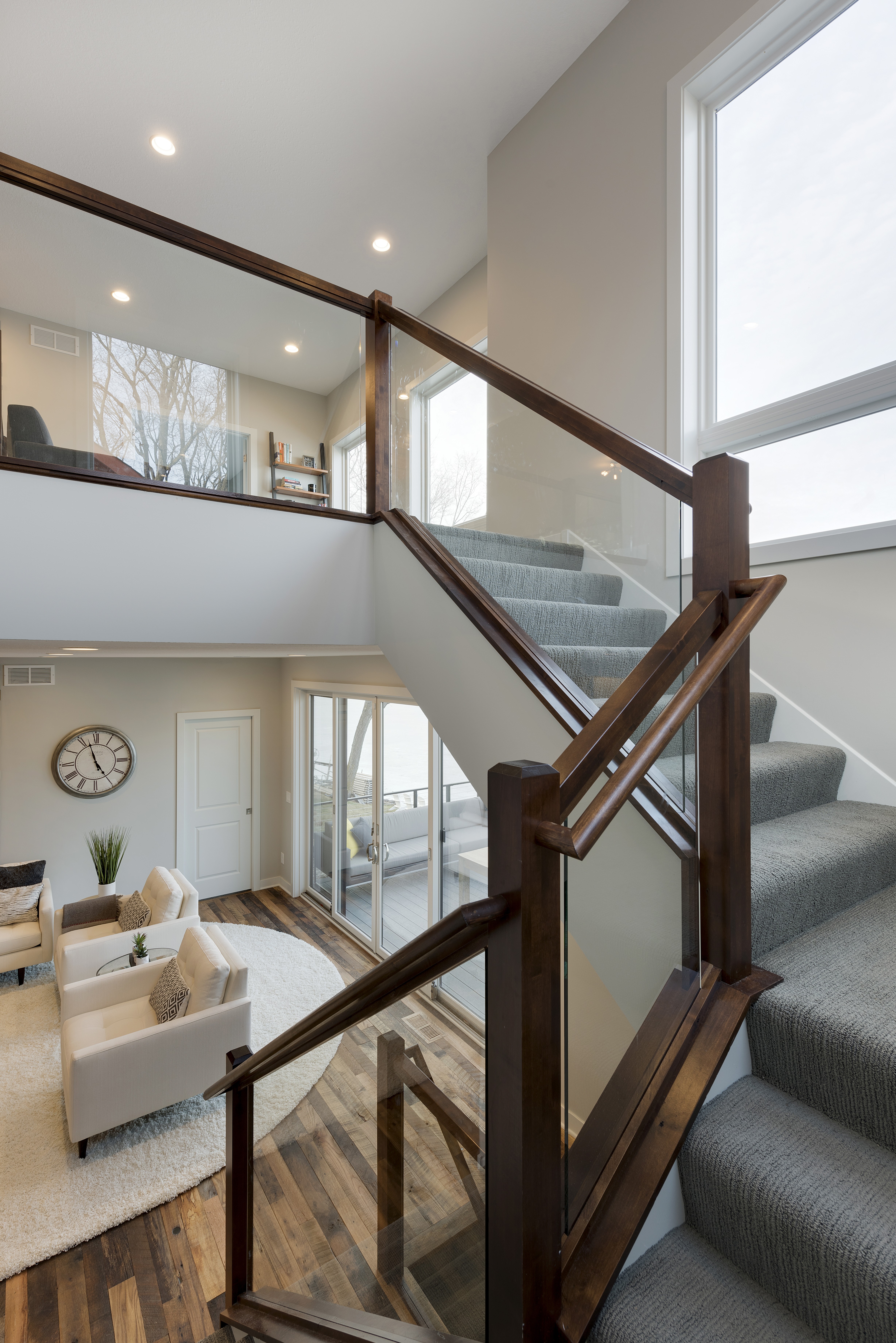 A modern staircase with wooden handrails and glass panels leading to an airy living space.
