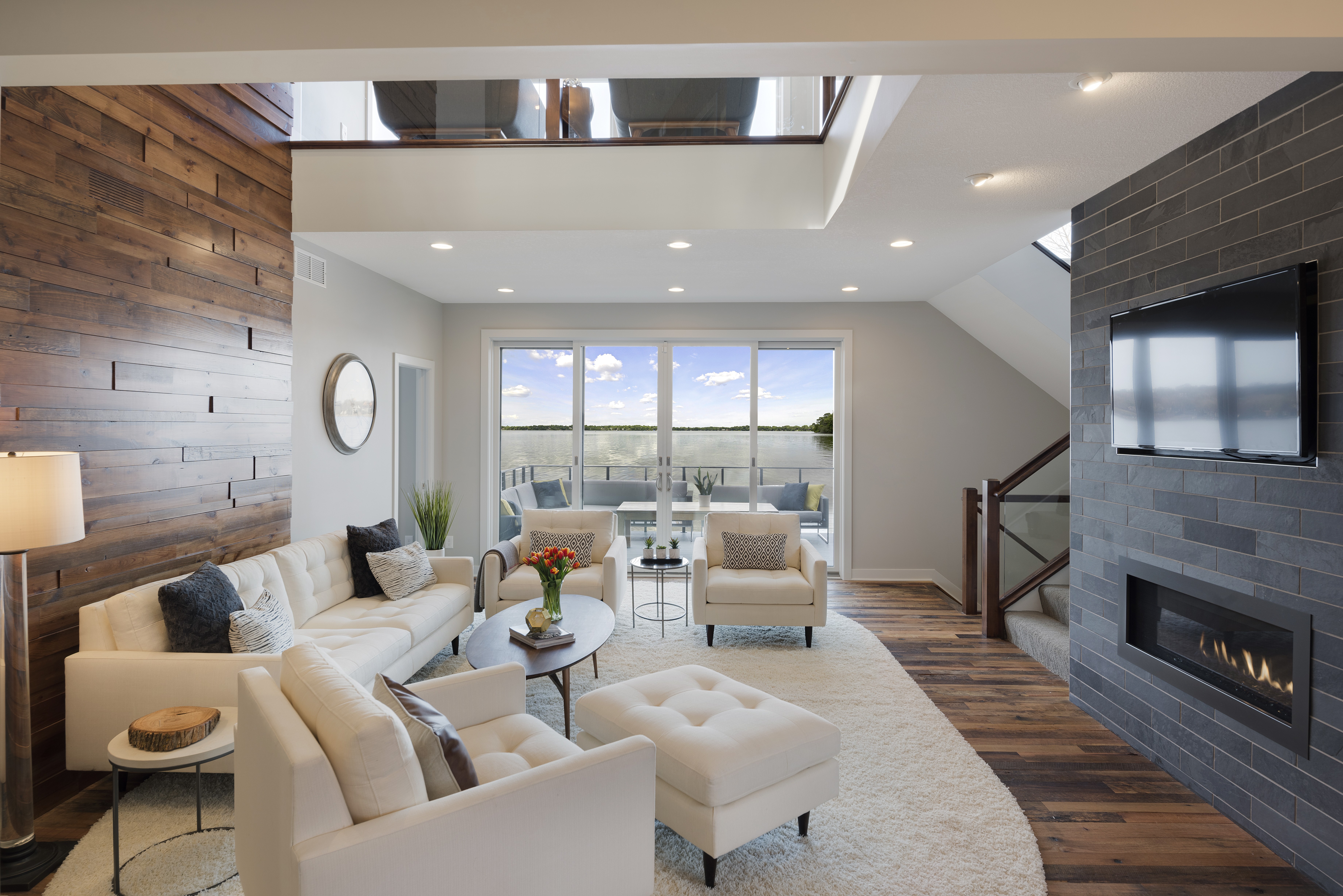 A modern living room with a stunning view of water, featuring stylish furniture and warm decor.