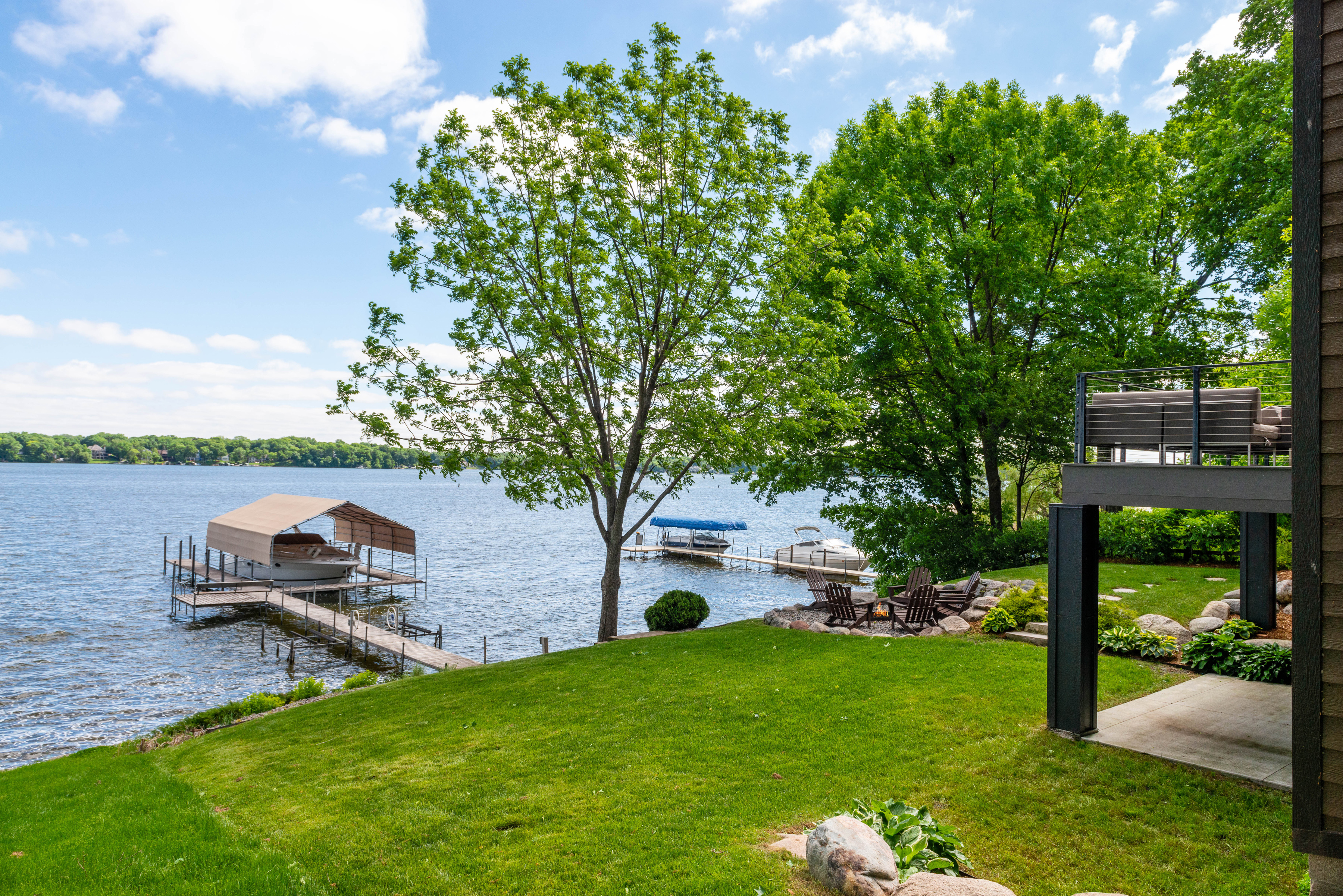 A tranquil lakeside view featuring lush greenery and a boat dock.