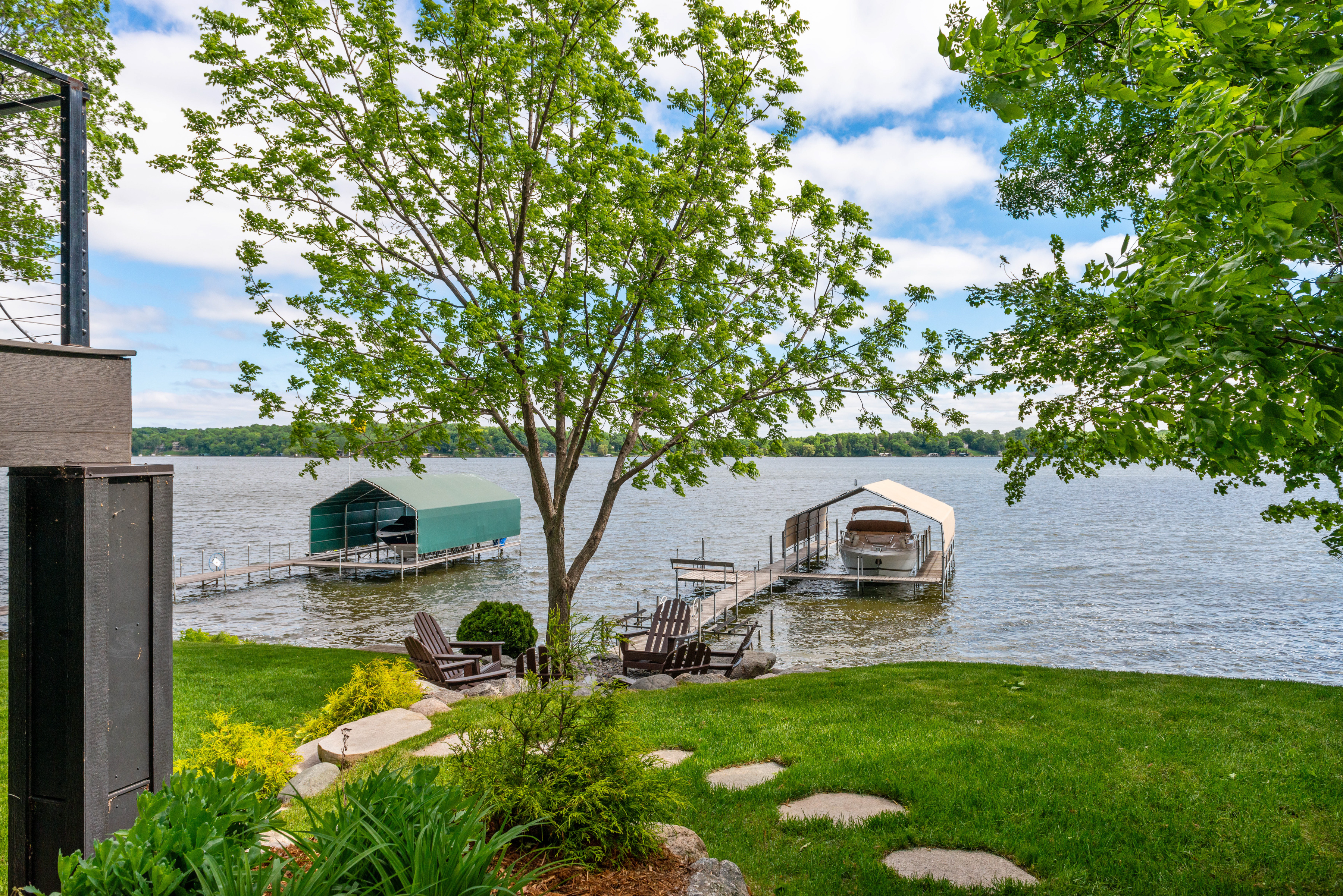 A picturesque lakeside view with docks and Adirondack chairs.