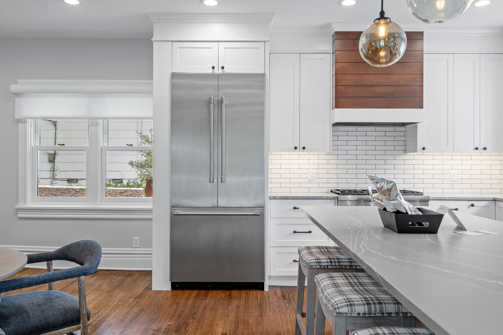 A modern kitchen featuring stainless steel appliances, white cabinetry, and a chic island.
