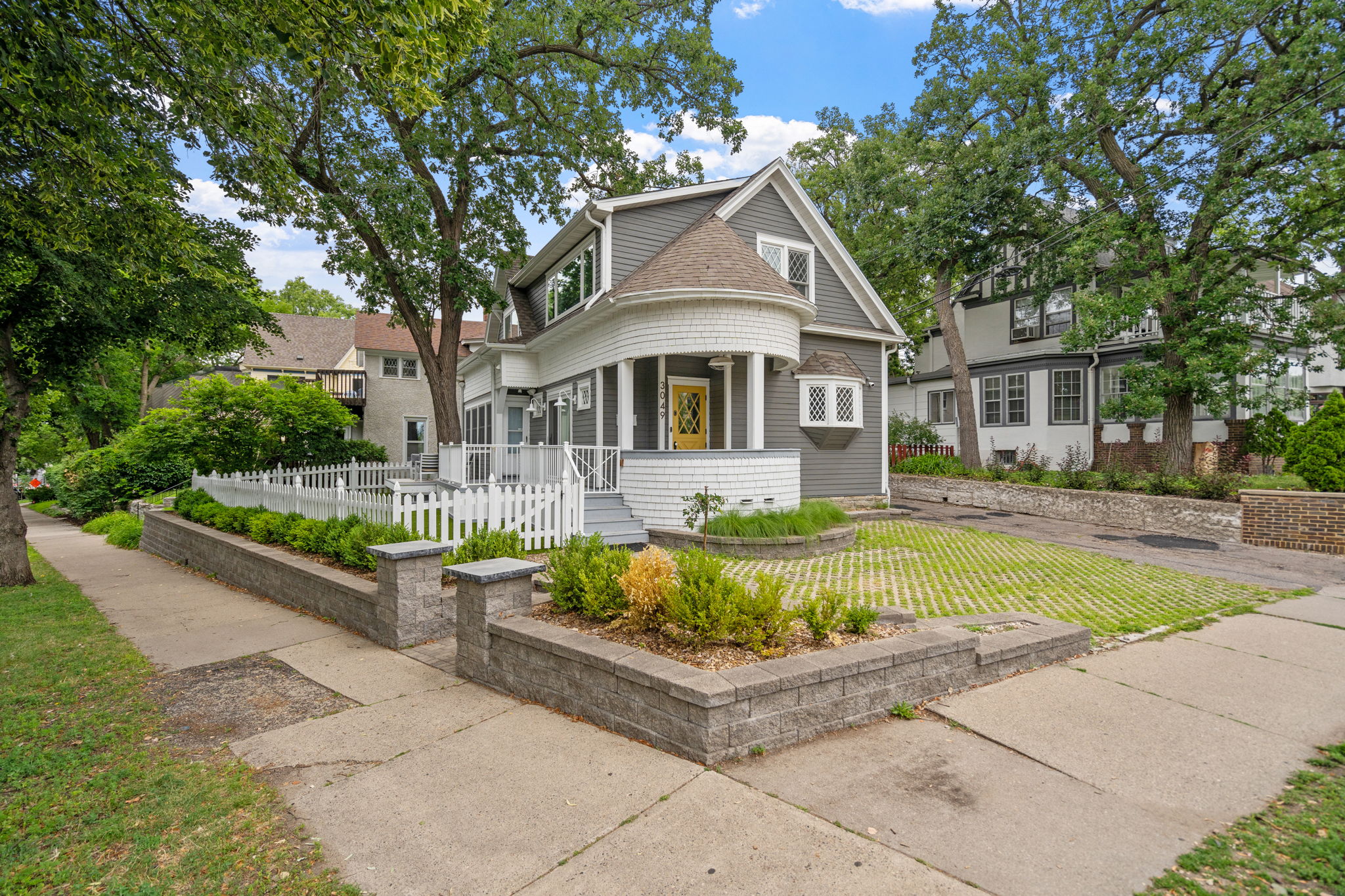 A picturesque house featuring a unique design with a circular porch and bright yellow door.