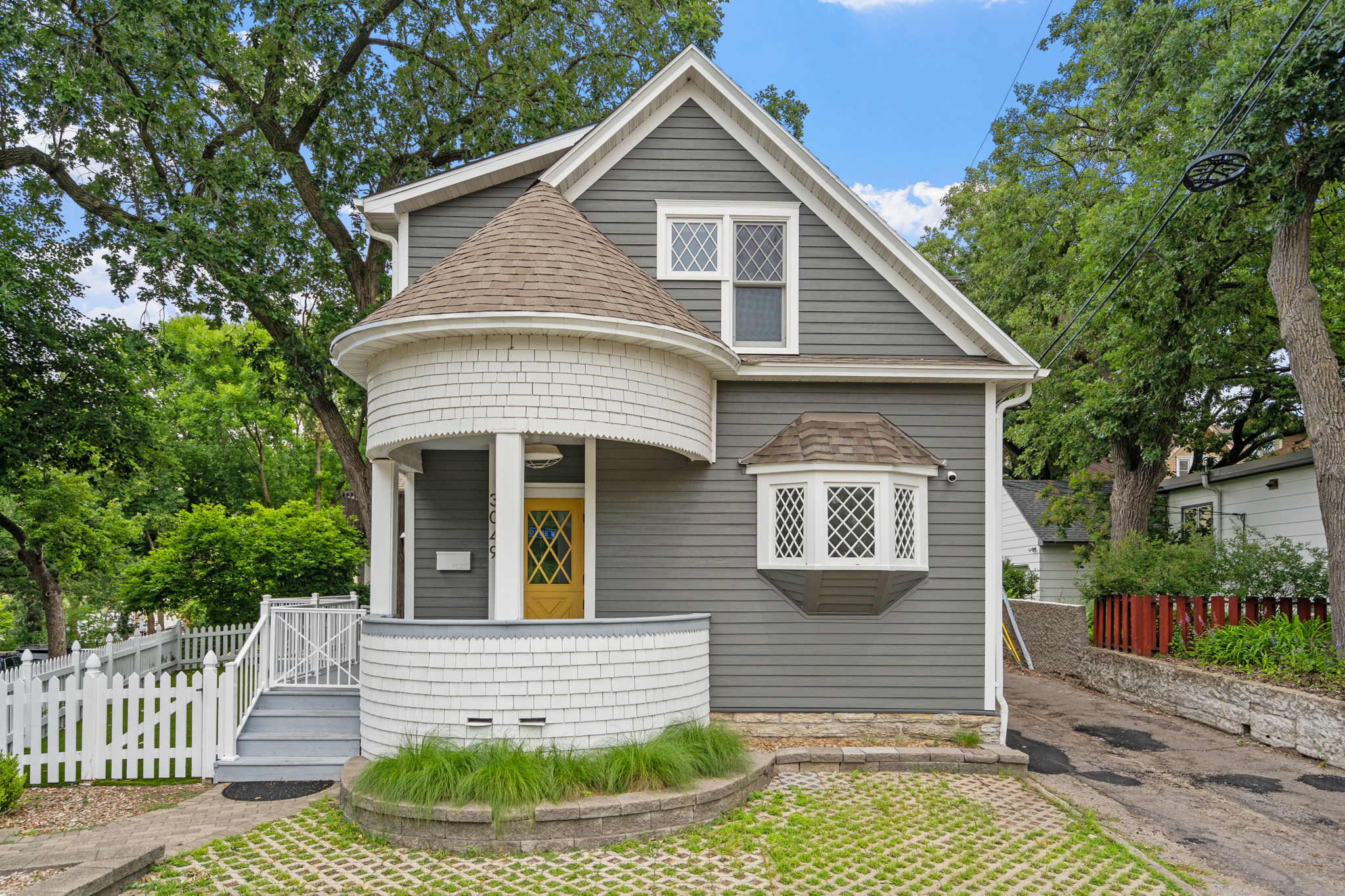 Charming grey house with a turret entrance and vibrant yellow door.