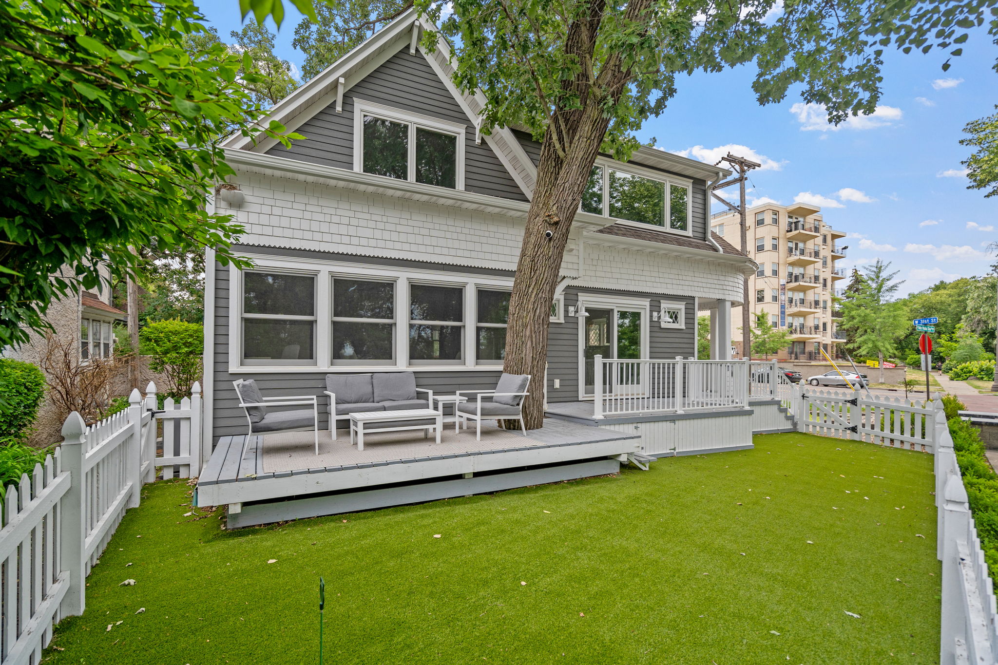 A cozy two-story home with a modern deck and green lawn.